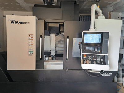 "Hyundai WIA F500 Plus CNC" staklės iš priekio, su skaitmeniniu valdymo skydeliu ir saugos etiketėmis.