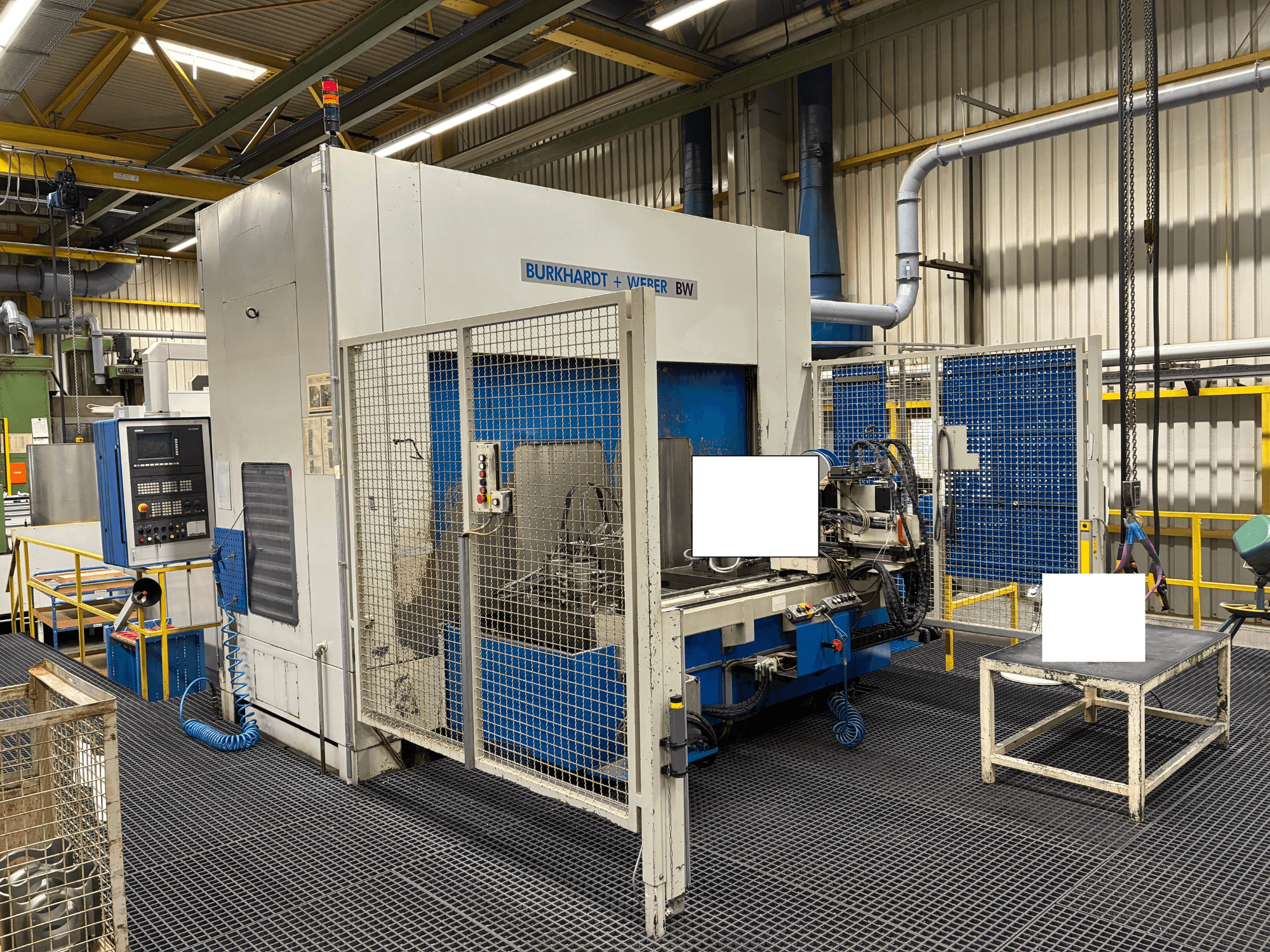 "Burkhardt + Weber BW" apdirbimo centras, vaizdas iš priekio, su valdymo skydeliu ir apsauginiu gaubtu, įrengtas pramoninėje aplinkoje.