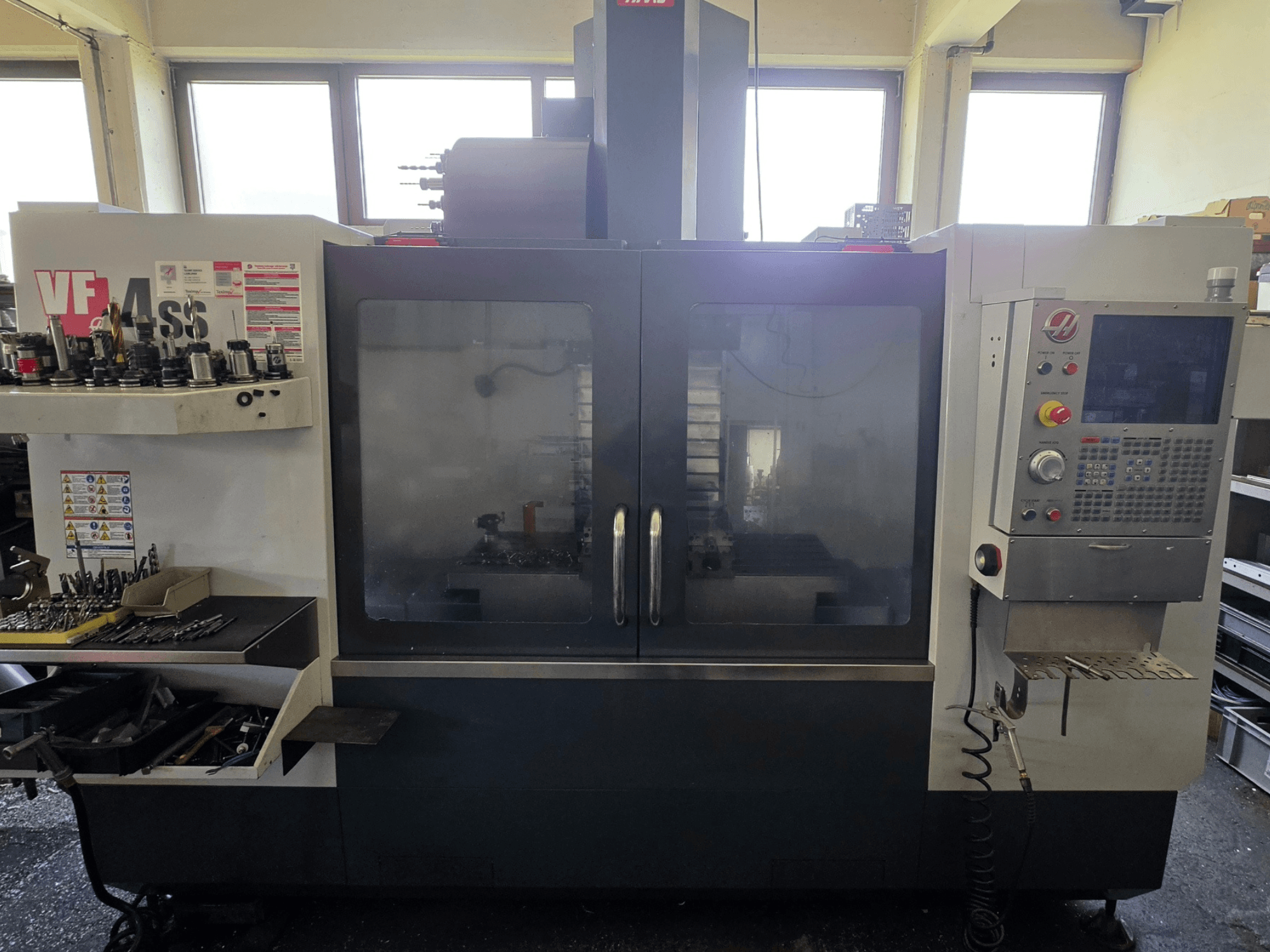 HAAS VF 34SS vertikalaus apdirbimo centro priekinis vaizdas, kuriame matomas valdymo skydelis ir įrankių laikymo vieta.