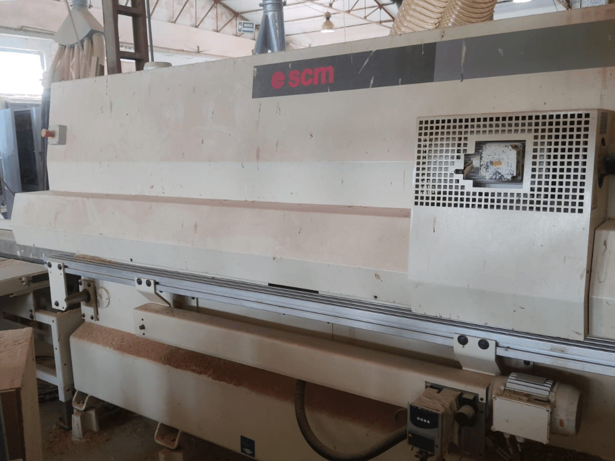 CNC medžio apdirbimo centras „SCM Windor60“, vaizdas iš priekio. Matomi staklių valdymo elementai ir dulkių surinkimo sistema, o po jais – medžio drožlės.
