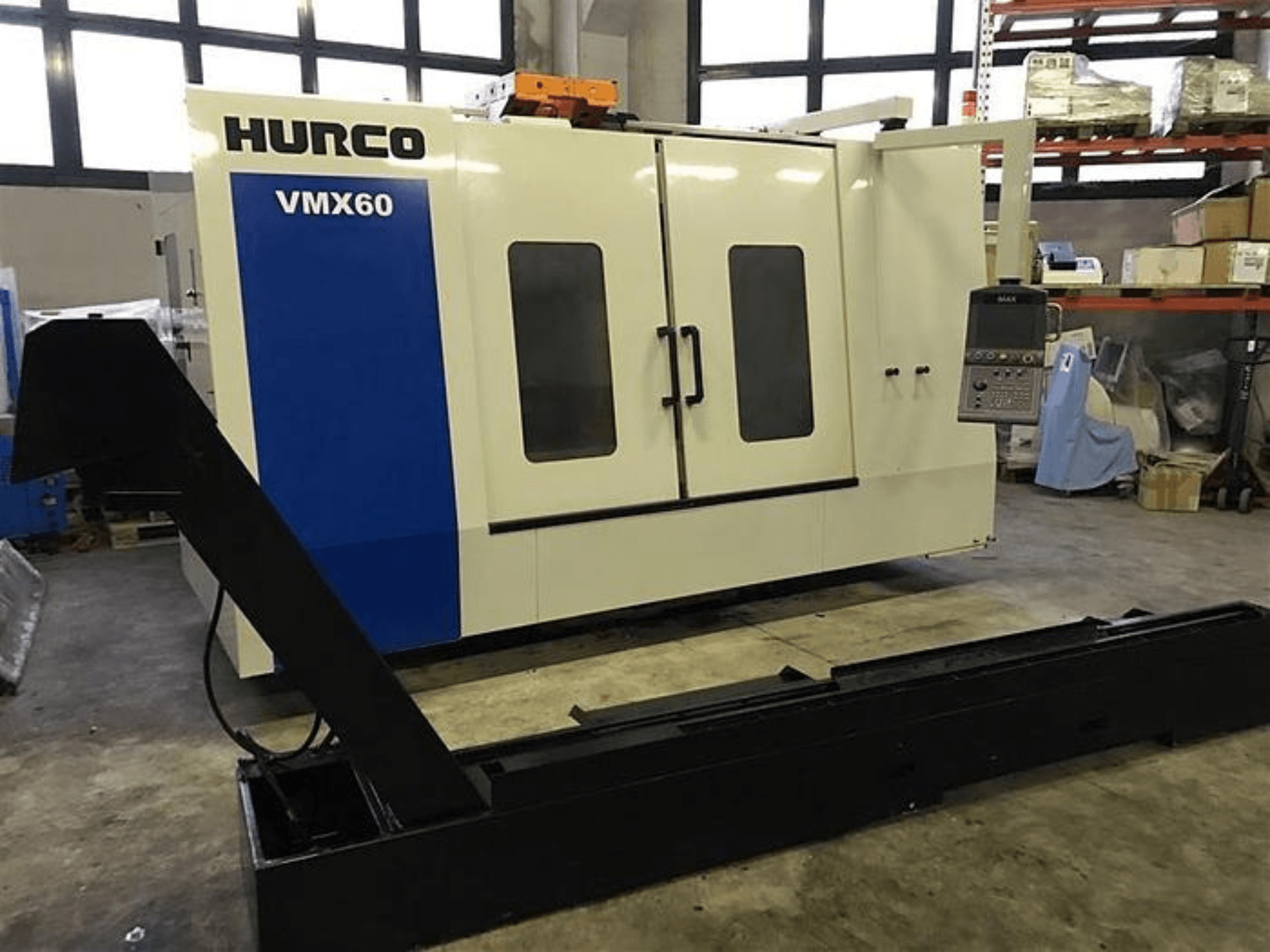 HURCO VMX60 CNC staklės dirbtuvėse, vaizdas iš priekio, su valdymo skydeliu ir pritvirtintu juodu atraminiu bėgiu.