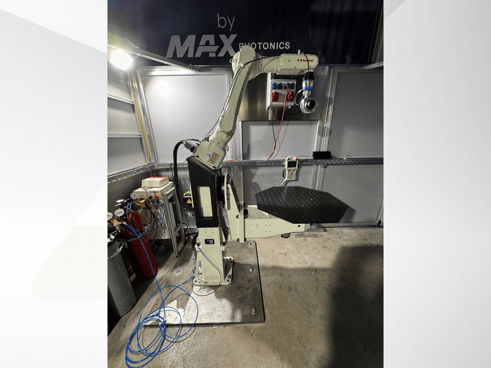 "Max Photonics" roboto rankos aparatas, vaizdas iš priekio, su juoda perforuota platforma ir valdymo skydeliu su matuokliais ir kabeliais.