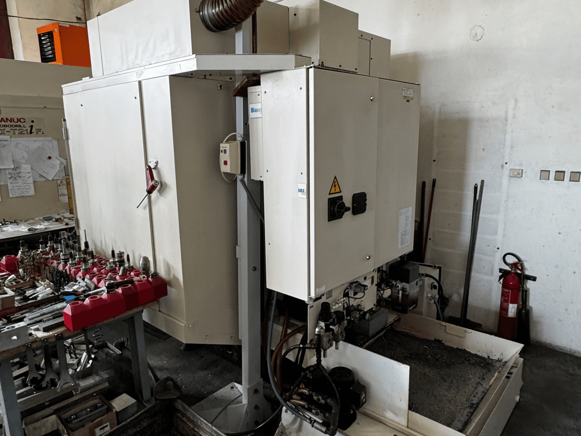 FANUC Robodrill alpha-T21iFL vertikalus apdirbimo centras, šoninis vaizdas, kuriame matomas valdymo skydelis, įrankiai ir darbo vieta.