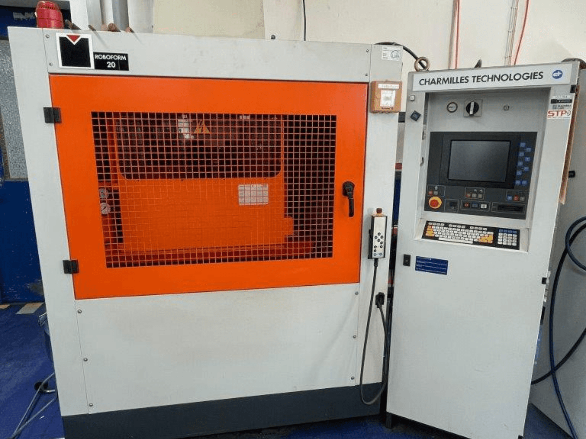 "AgieCharmilles Robofrom 20" štampavimo EDM staklės, vaizdas iš priekio su valdymo skydeliu ir oranžinėmis apsauginėmis grotelėmis.