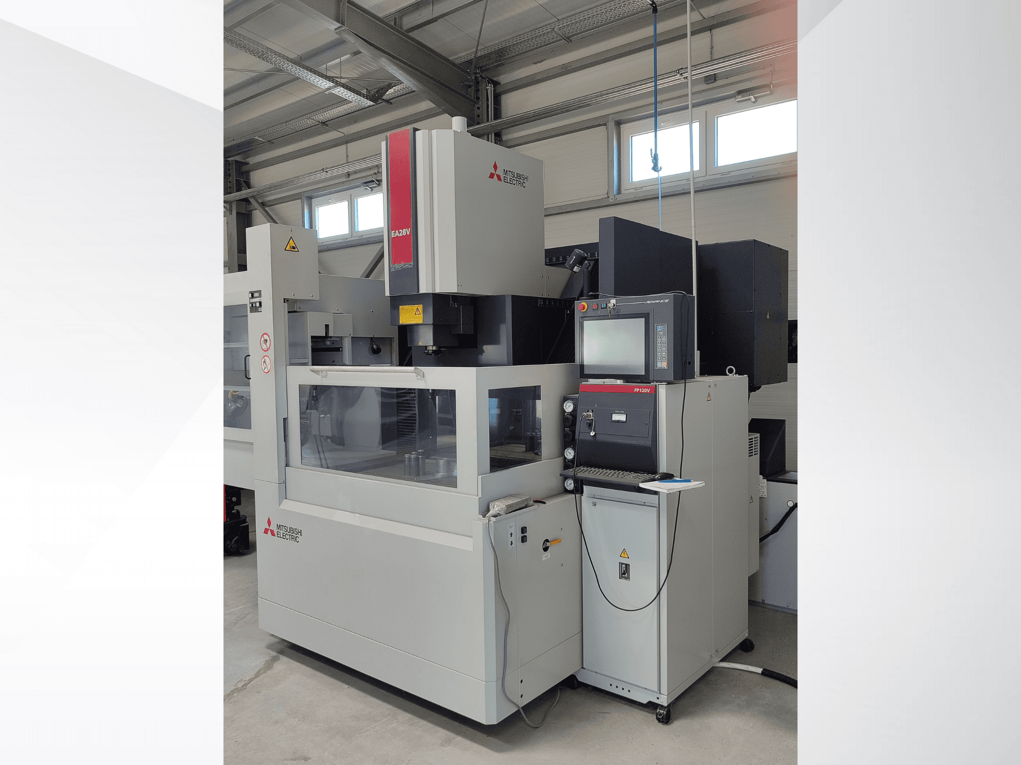 "Mitsubishi Electric EA32V" vielos pjovimo EDM staklės iš šono, su valdymo skydeliu ir per stiklą matoma darbo zona.