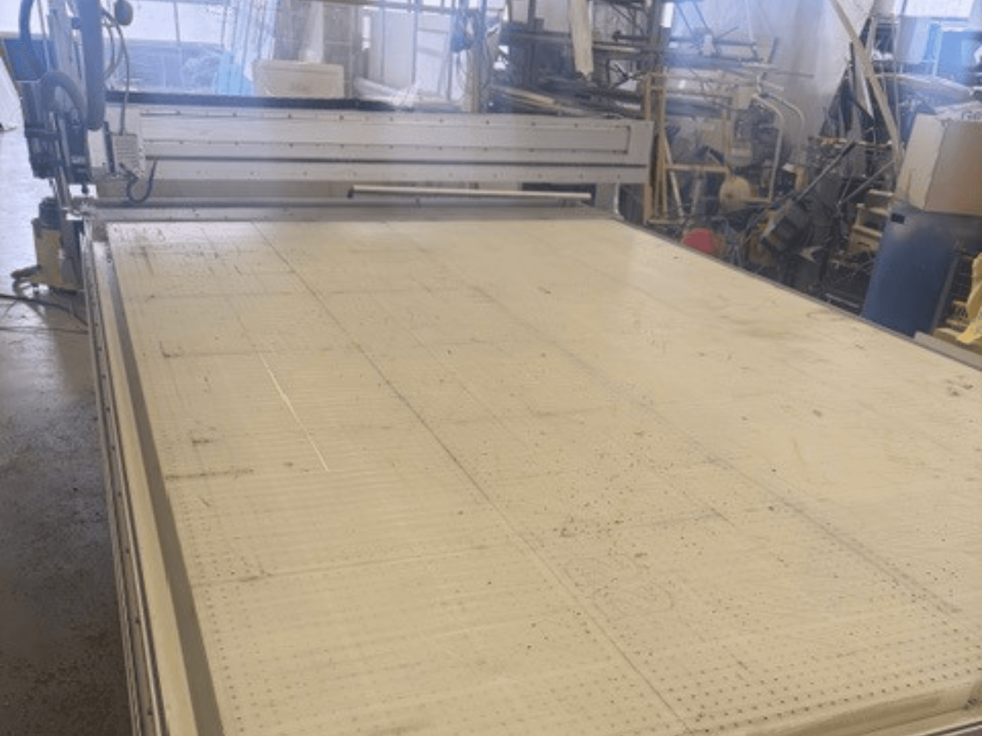 Didelės pjovimo staklės su plokščiu paviršiumi, matomas rėmas ir kreipiamasis bėgis; žiūrint kampu dirbtuvėse.