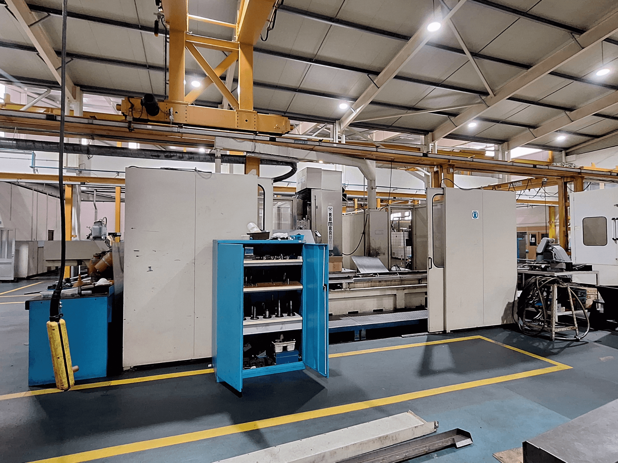 Portalinės frezavimo staklės Rambaudi RX 1250, vaizdas iš priekio su įrankių saugykla, erdvioje pramoninėje darbo vietoje.