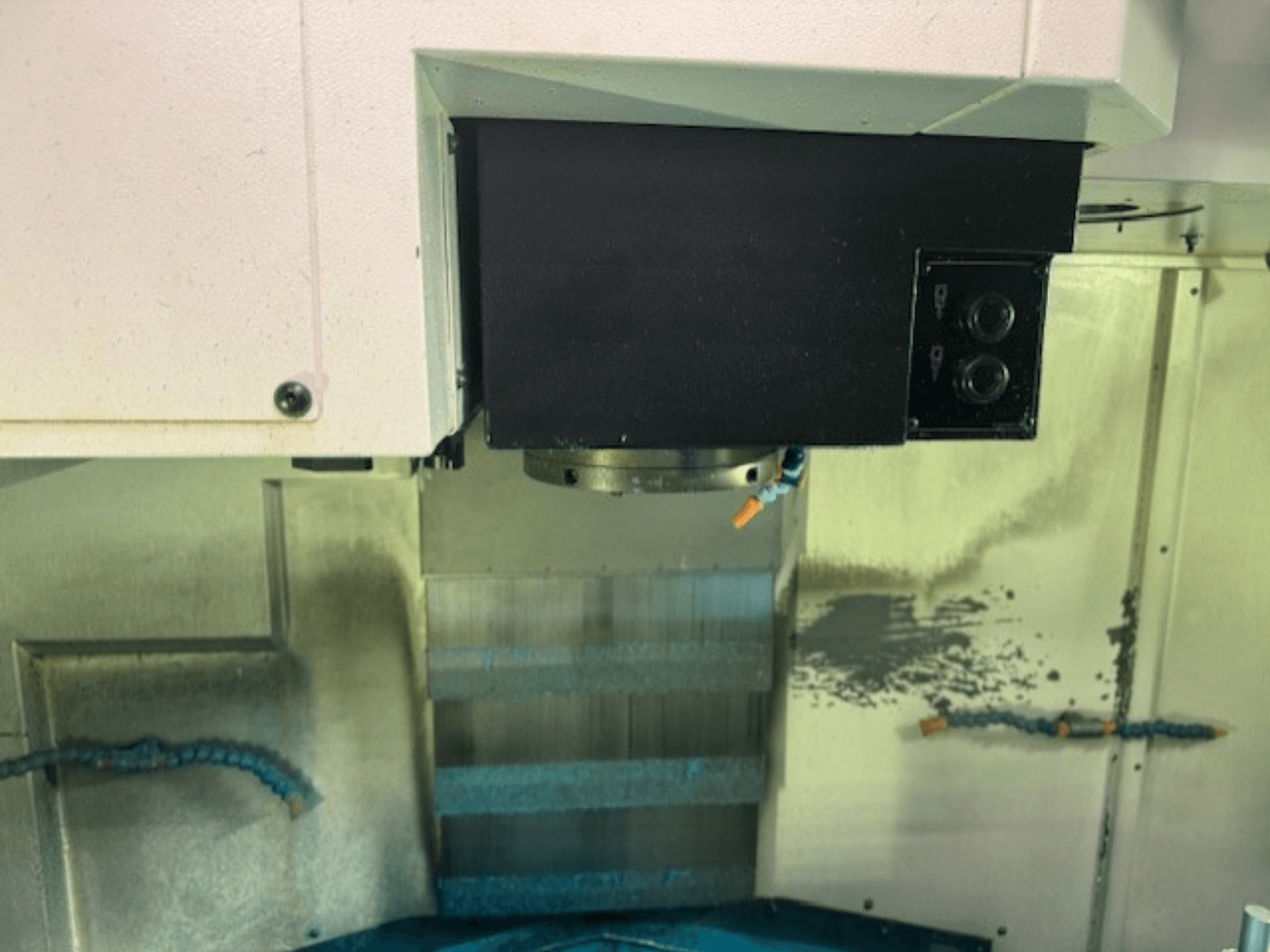 CNC frezavimo staklių valdymo skydo ir įrankių laikiklio stambiu planu, kuriame matyti prekės ženklo detalės, mygtukai ir darbo paviršius.