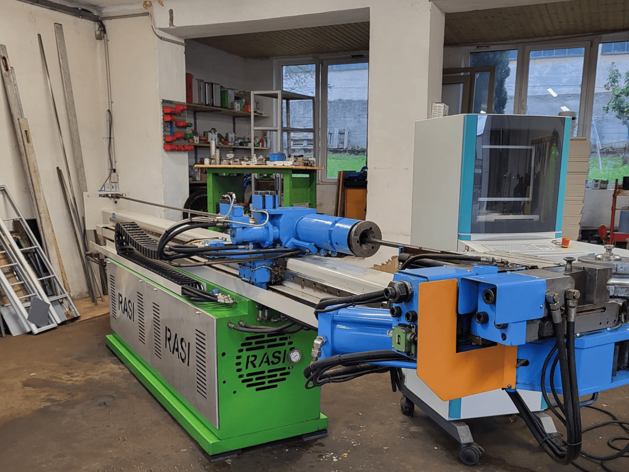 Rasi S 80.6 L G-V3C50 staklės dirbtuvėse, šoninis vaizdas, kuriame matyti mėlynos ir žalios spalvos komponentai ir valdymo skydelis.