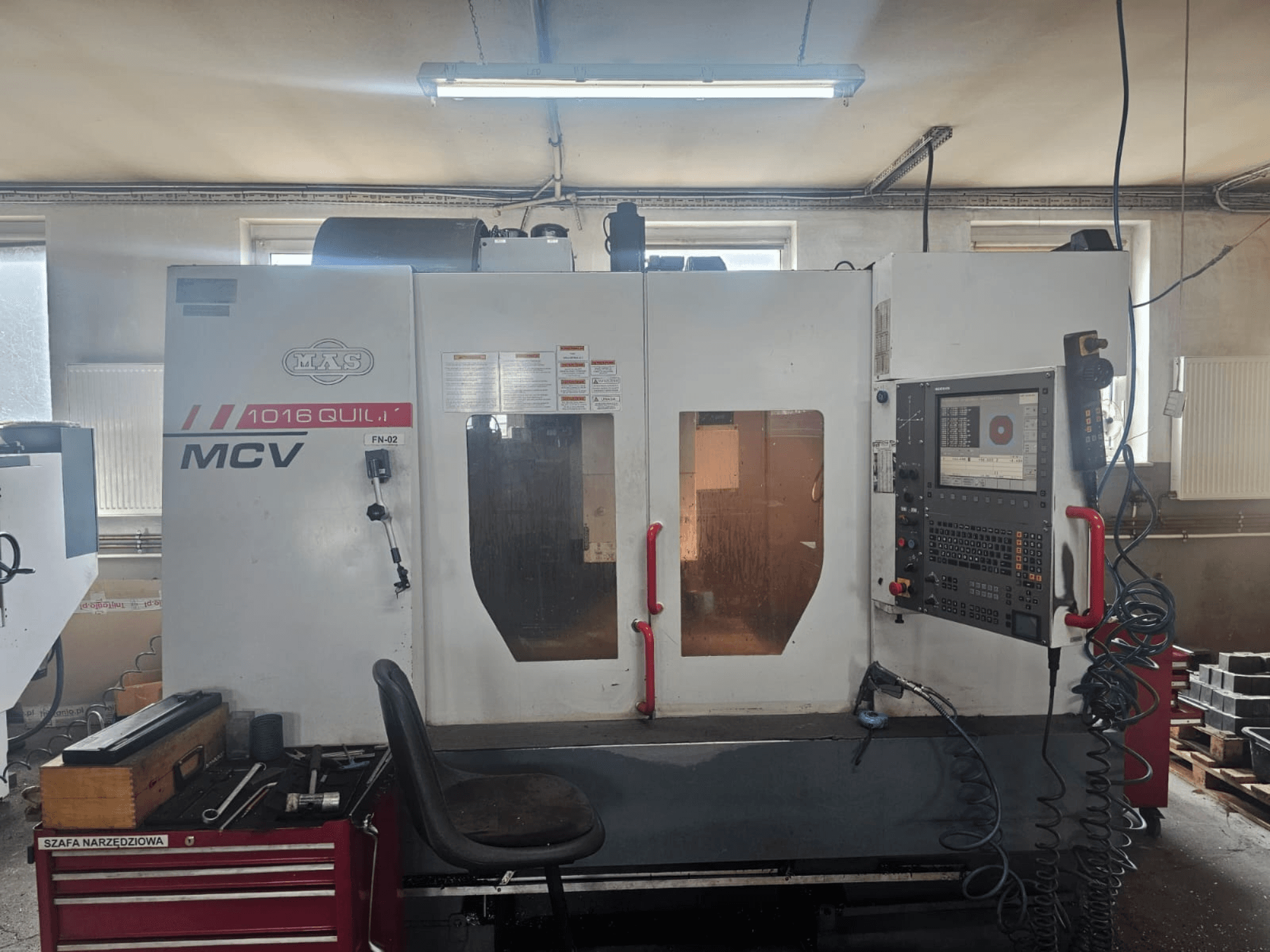 MVS MCV 1016 QUILL CNC staklės, vaizdas iš priekio, valdymo skydelis, įrankių stalčius ir darbo vieta su įrankiais.