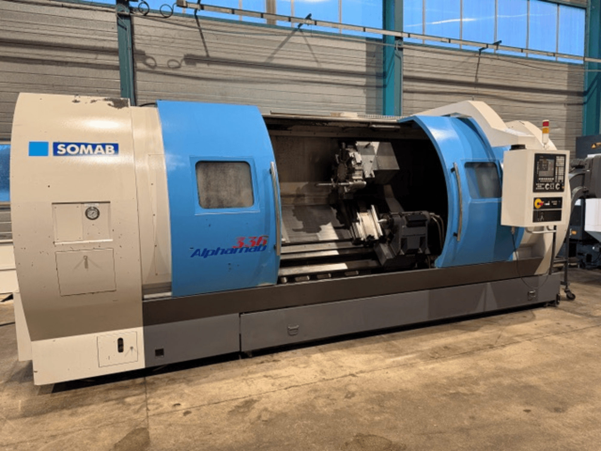 SOMAB Alpha 336 CNC tekinimo staklės, vaizdas iš priekio, mėlynos ir pilkos spalvos korpusas ir valdymo skydelis šone.