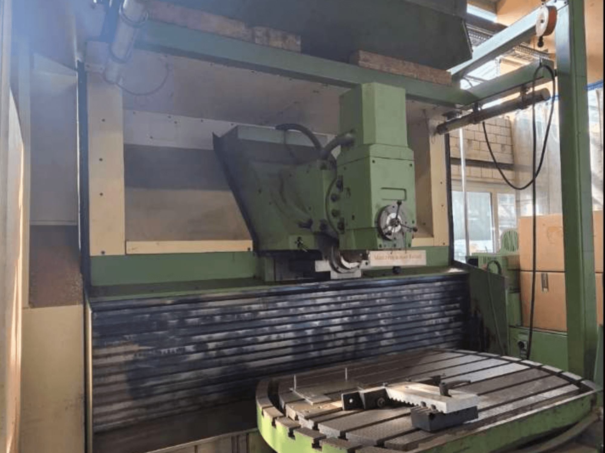 MAHO MH1000 C universalaus apdirbimo centro priekinis vaizdas, kuriame matyti žalia konstrukcija, suklys ir sukamasis stalas su ruošiniu.