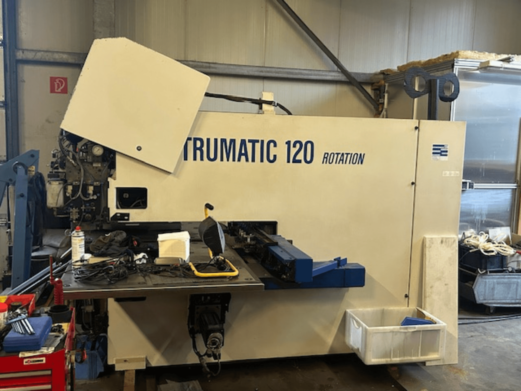 TRUMPF Trumatic 120R CNC perforavimo staklės dirbtuvėse, vaizdas iš priekio, kuriame matomas valdymo skydelis ir įrankiai ant stalo.