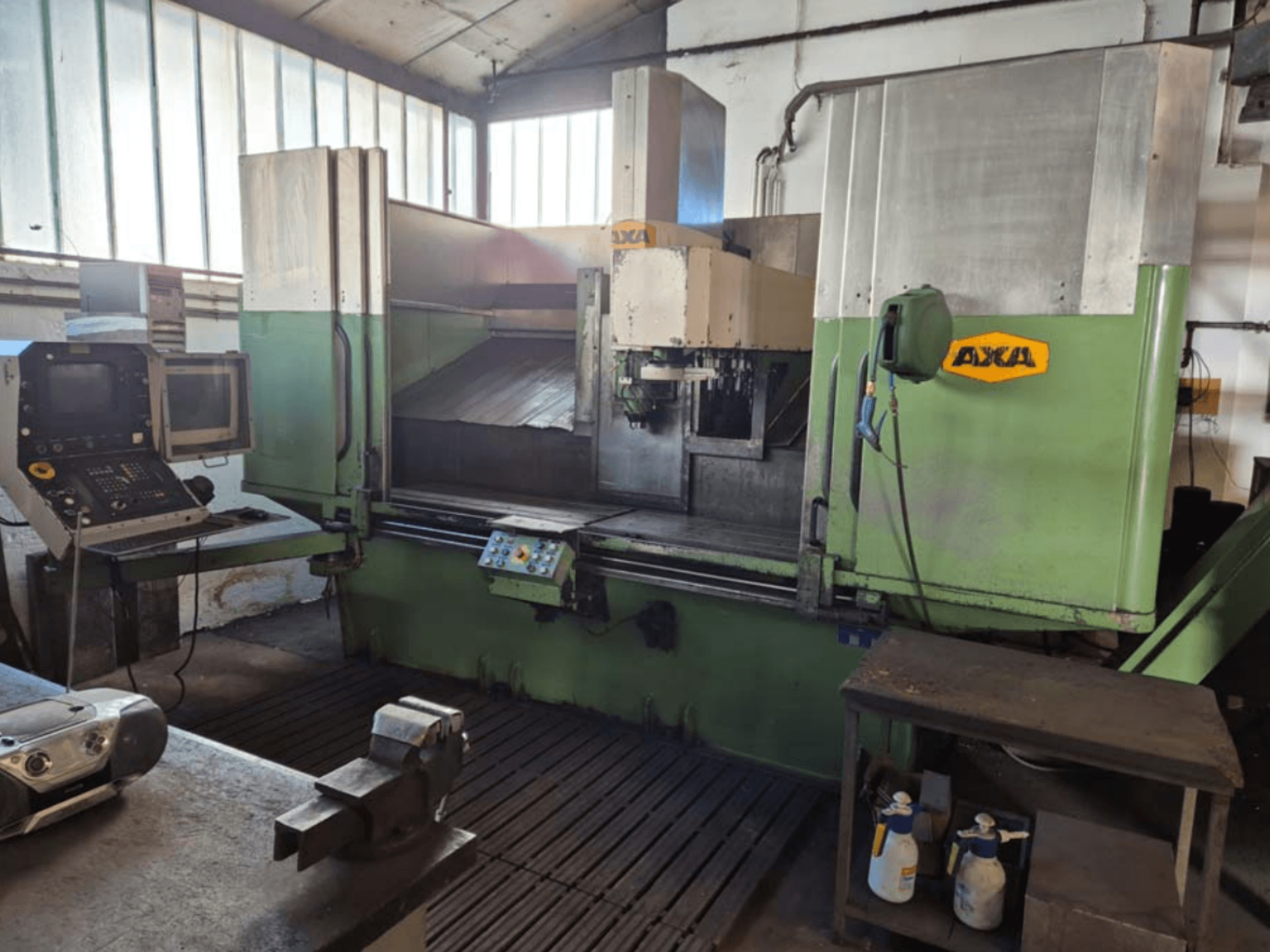 AXA VSC-2M vertikalusis apdirbimo centras, vaizdas iš priekio, valdymo skydelis ir darbo zona su pjovimo įrankiais ir valymo reikmenimis.