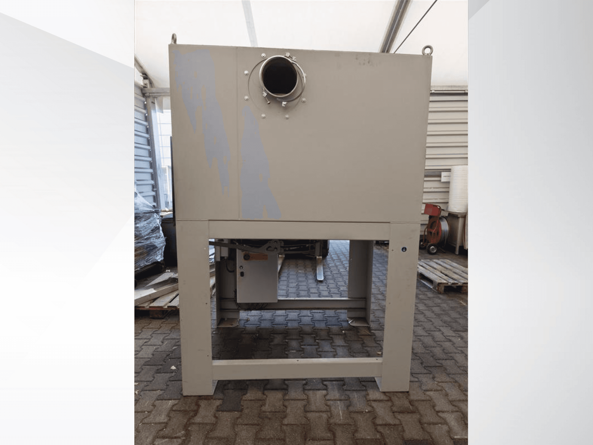 Pilkas pramoninis dulkių surinktuvas iš priekio, su didele apvalia anga, sumontuotas ant tvirto pagrindo.