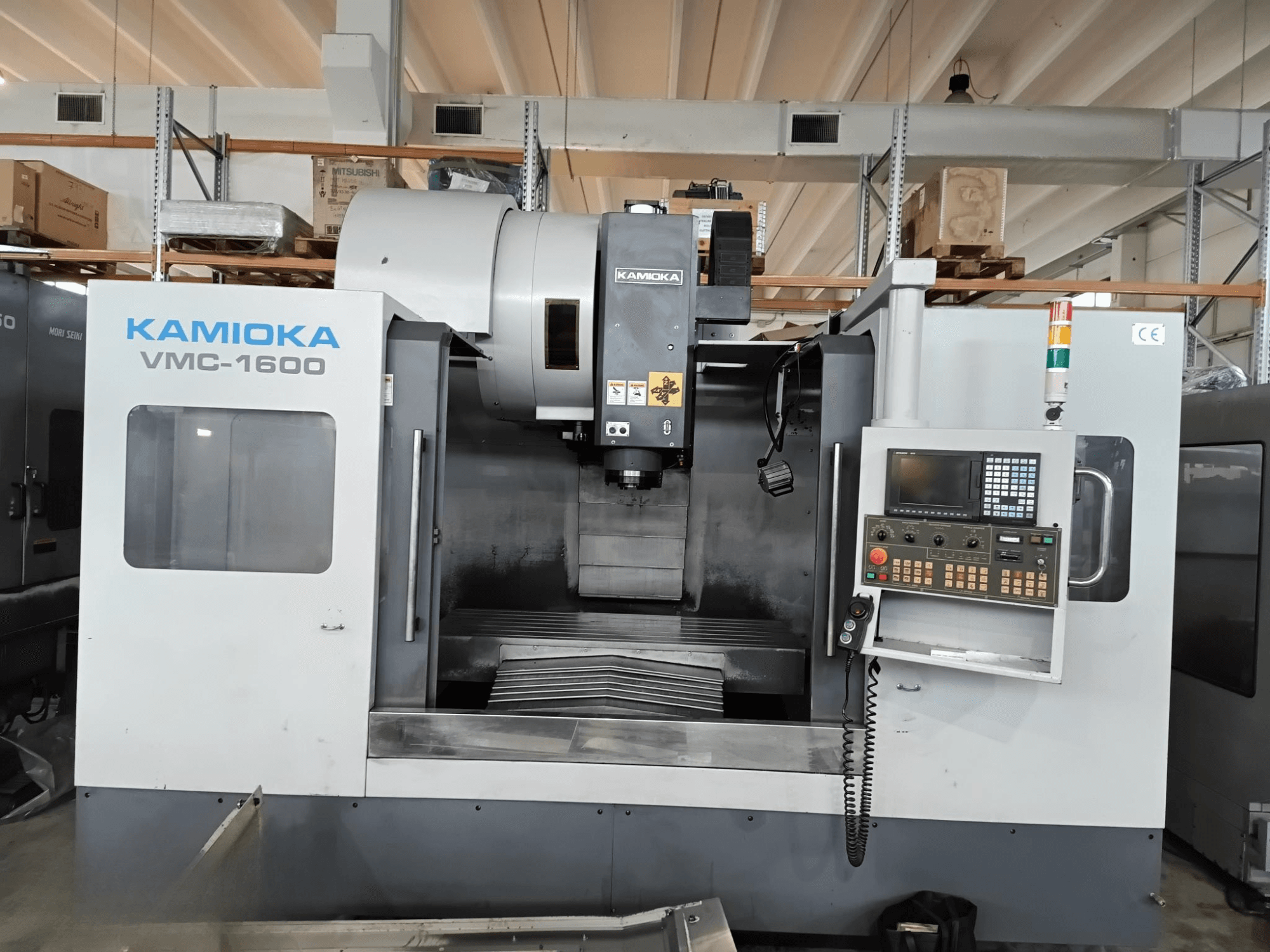 Kamioka VMC-1600 vertikalus apdirbimo centras gamykloje, vaizdas iš priekio su valdymo pultu ir matoma apdirbimo lova.