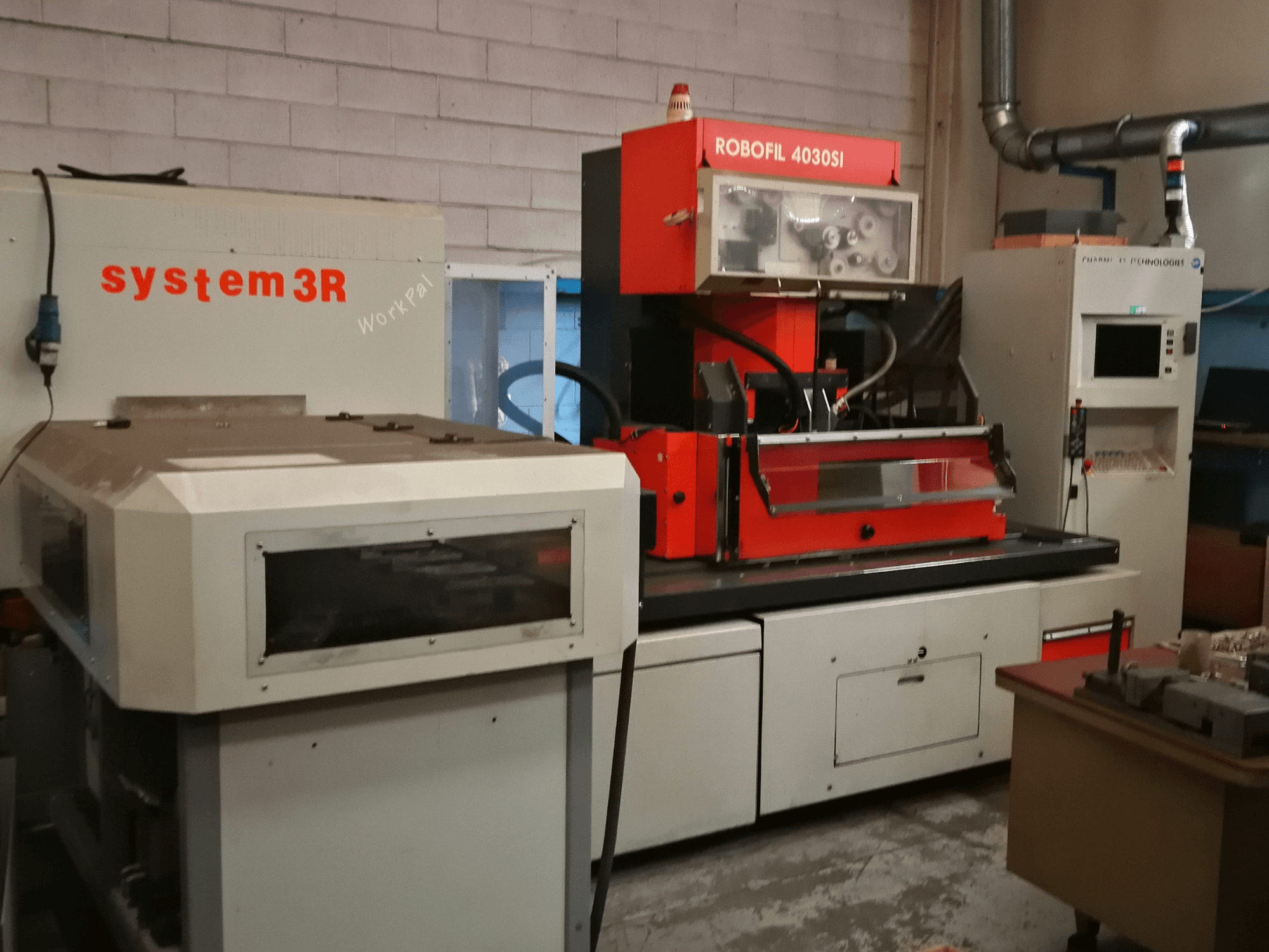 CHARMILLES ROBOFIL 4030 Si vielos EDM staklių vaizdas iš priekio, raudonos ir pilkos spalvos išorė ir šalia esanti system3R darbo vieta.