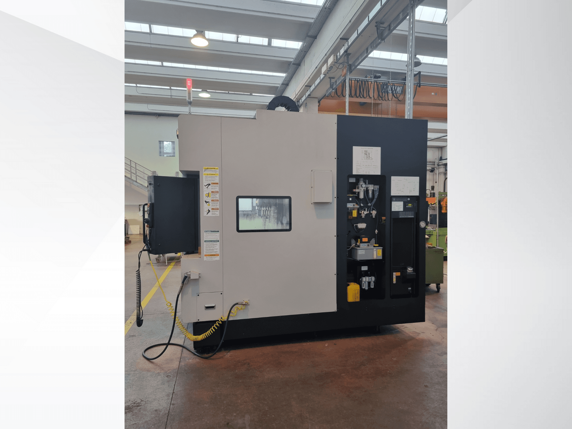 Pramoninės mašinos šoninis vaizdas, valdymo skydelis su mygtukais, indikatoriais ir įspėjamąja saugos etikete.