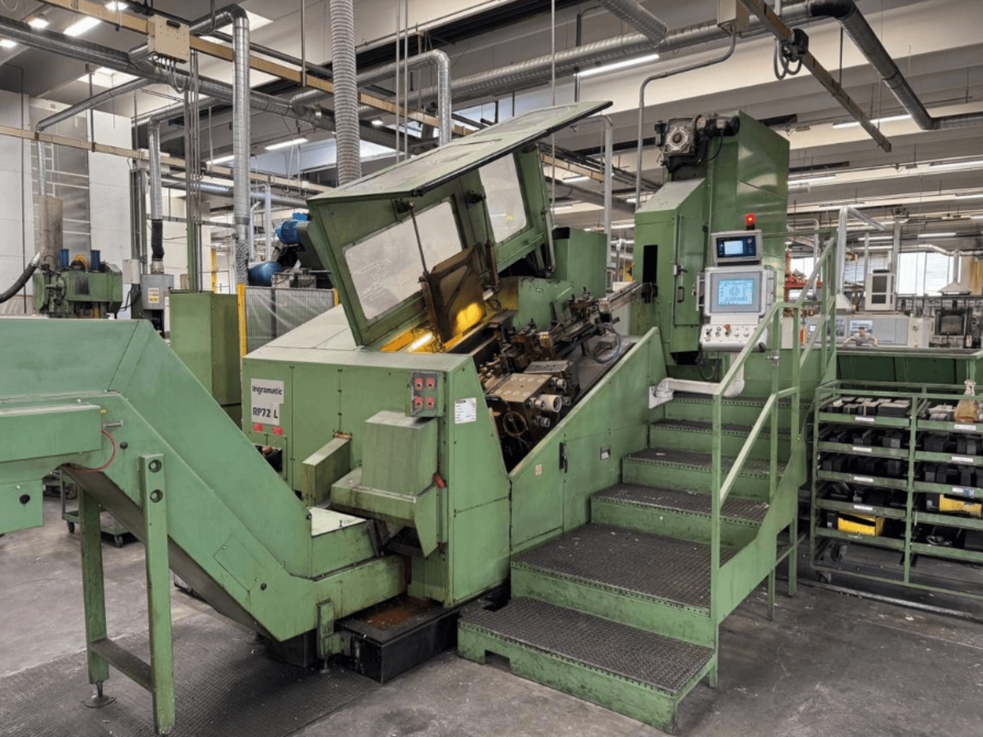 Žalios spalvos pramoninė mašina "Ingramatic RP72 L", vaizdas iš priekio; turi valdymo skydelį ir laiptelius su metalinių grotelių platforma.