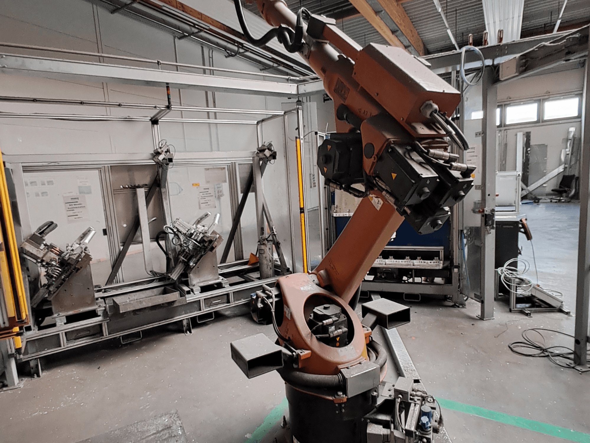 „KUKA KR 30L16-2“ roboto ranka pramoninėje aplinkoje, vaizdas iš šono, kuriame matomi rankos sąnariai ir griebtuvai.