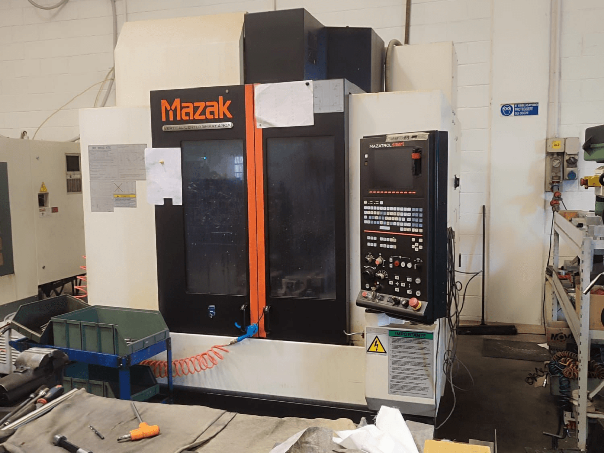 Vertikalaus apdirbimo centro Mazak VCS 430A priekinis vaizdas, kuriame matomas valdymo skydelis ir darbinės detalės dirbtuvėse.