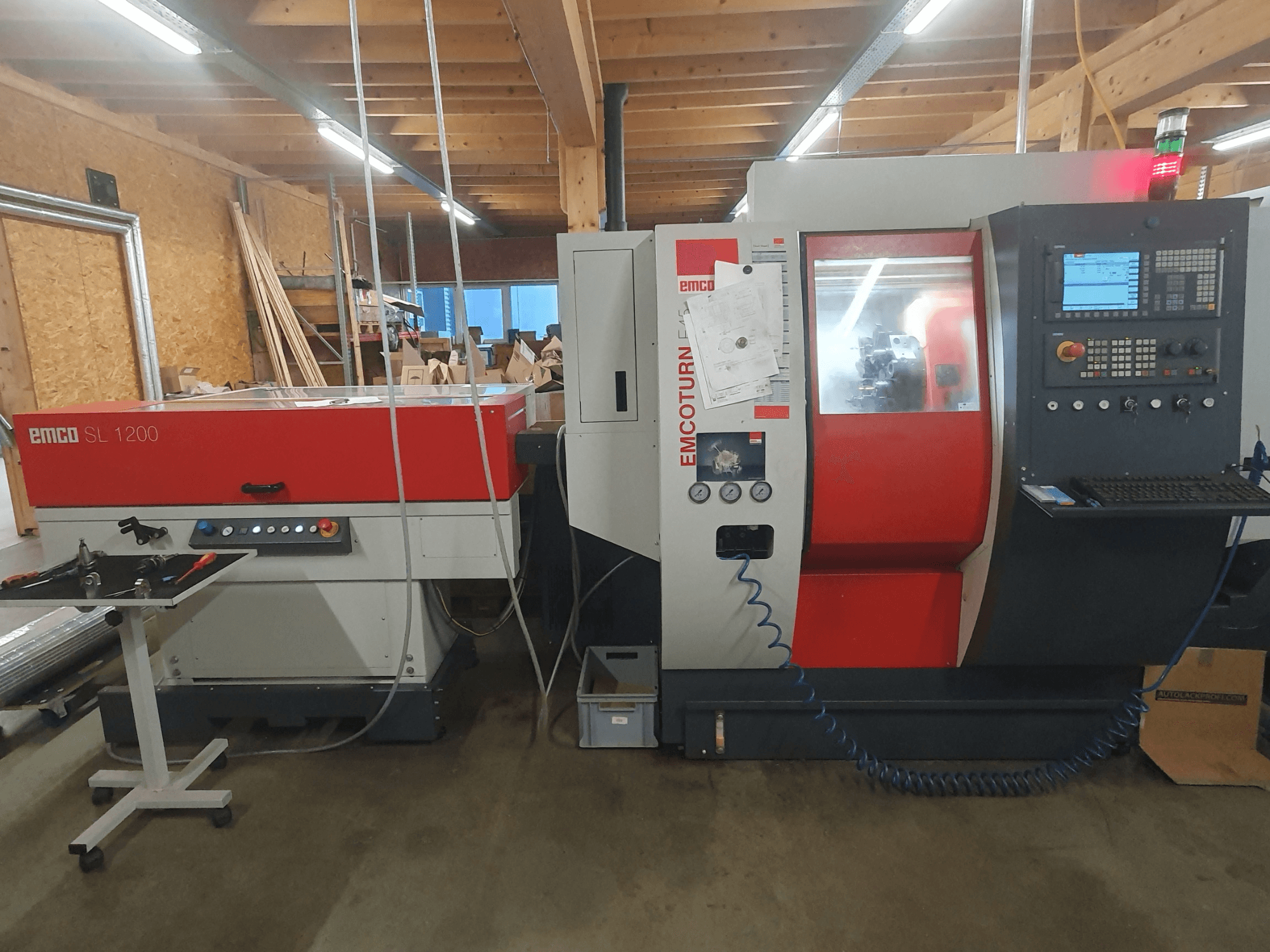 EMCO SL 1200 CNC tekinimo staklės ir EMCOturn; priekinis vaizdas, kuriame matomi valdikliai, ekranai ir veikimo indikatoriai dirbtuvėse.