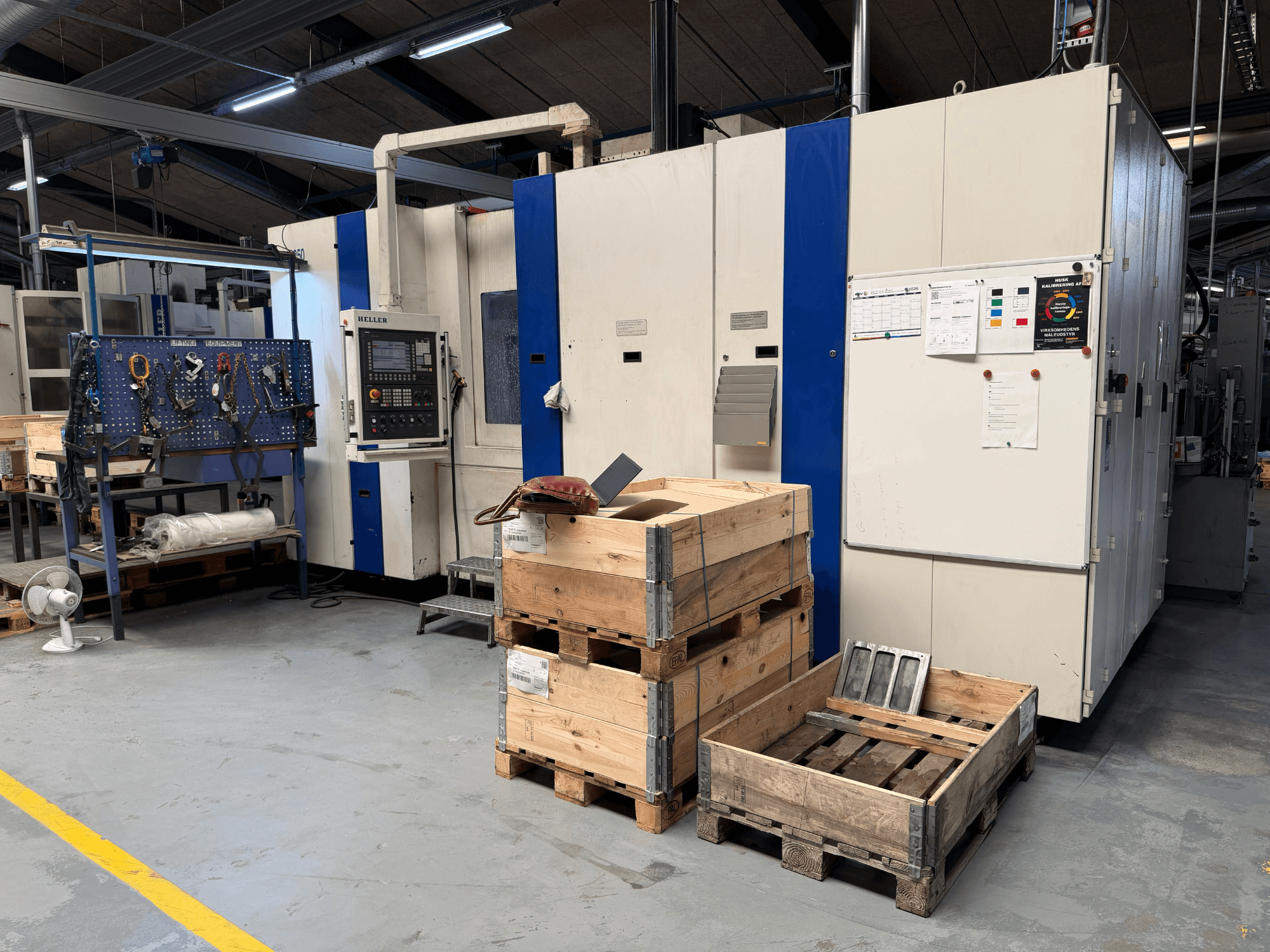 HORIZONTALUS MAŠINŲ CENTRAS HELLER MCH 250 dirbtuvėse, šoninis vaizdas, matomi mediniai padėklai ir įrankių stovas.