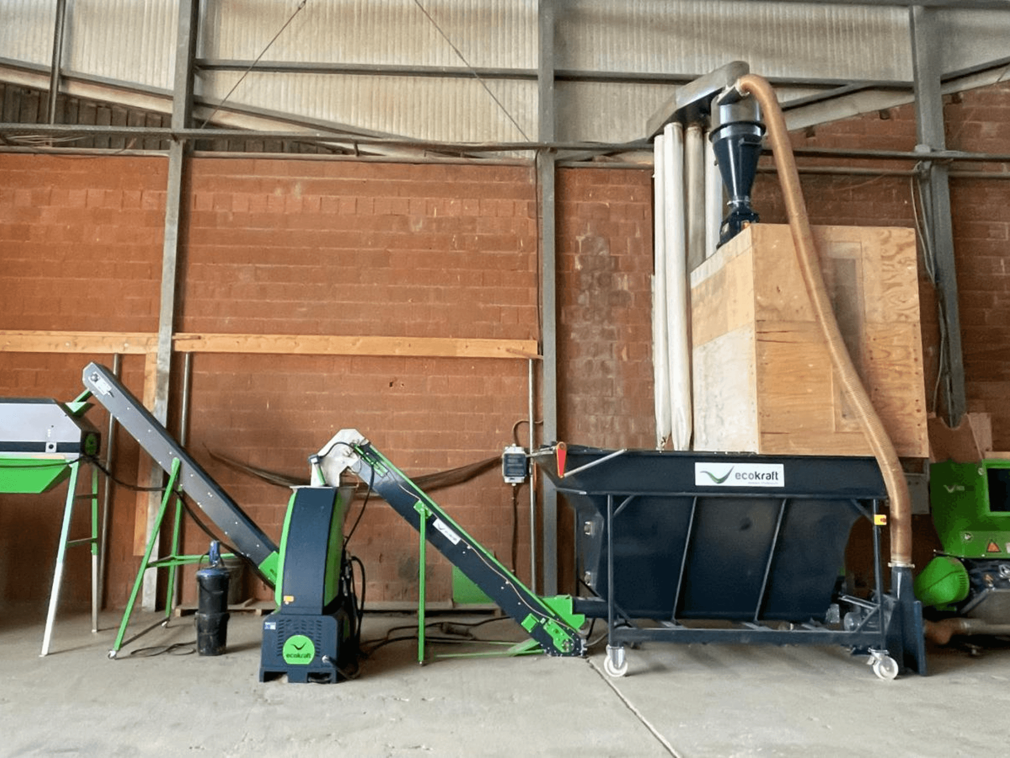 „ECOKRAFT LP 22“ staklės sandėlyje, su konvejeriu ir dulkių surinkimo sistema. Šoninis vaizdas, kuriame matomi funkciniai komponentai.