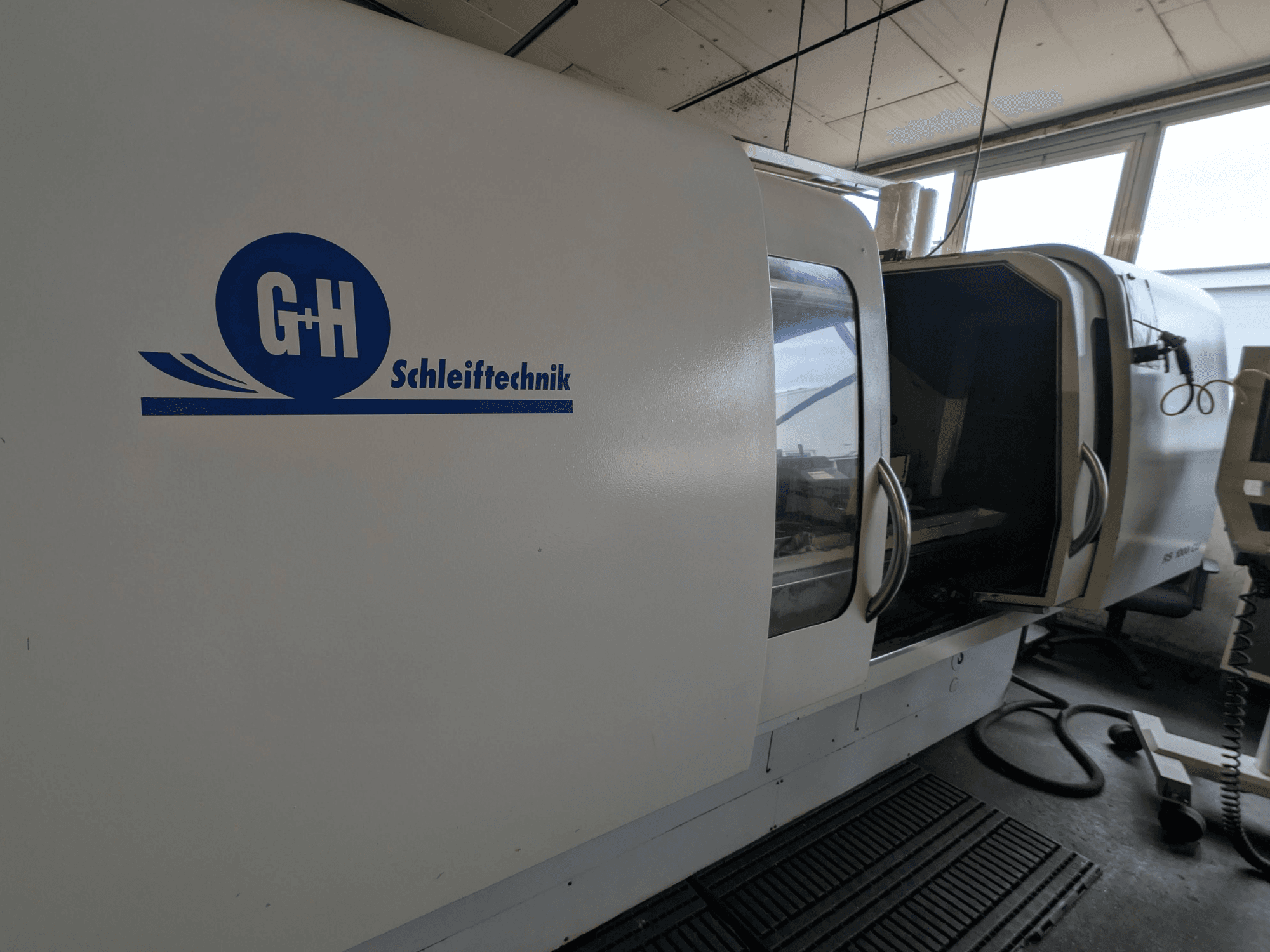 Cilindrinio šlifavimo staklės GEIBEL & HOTZ RS 1000 CU, šoninis vaizdas, kuriame matomas valdymo skydelis ir atidarytos prieigos durelės.