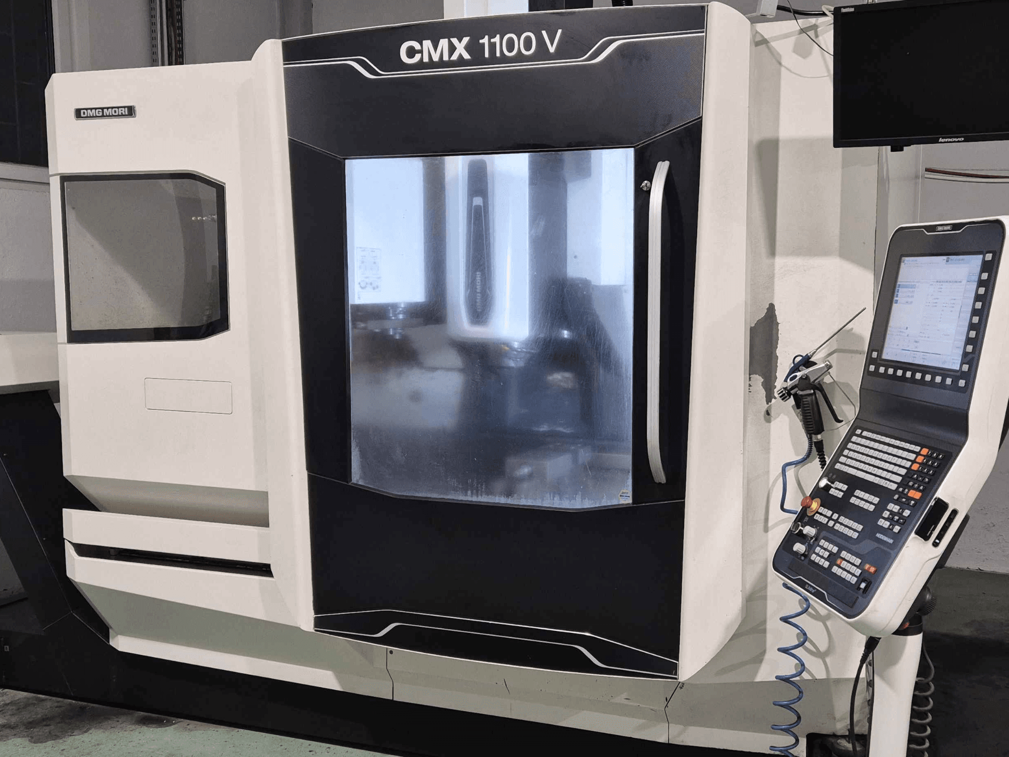 DMG Mori CMX 1100 V, CNC staklių vaizdas iš priekio, matomas valdymo skydelis, skaitmeninis ekranas ir aušinimo skysčio nustatymai.