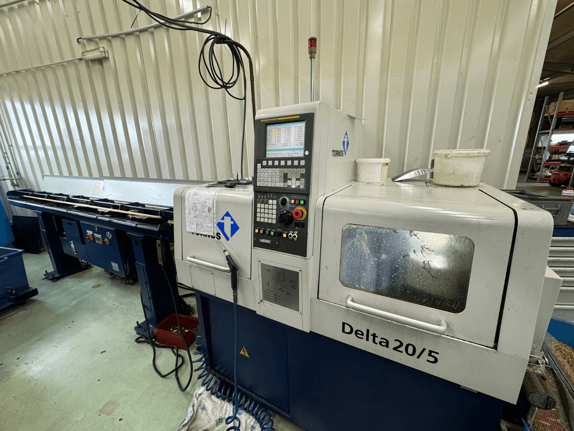 Torino Delta 20/5 CNC staklės, vaizdas iš priekio, su valdymo pultu ir darbo vieta. Graviruotas stiklas ir matomi laidai.
