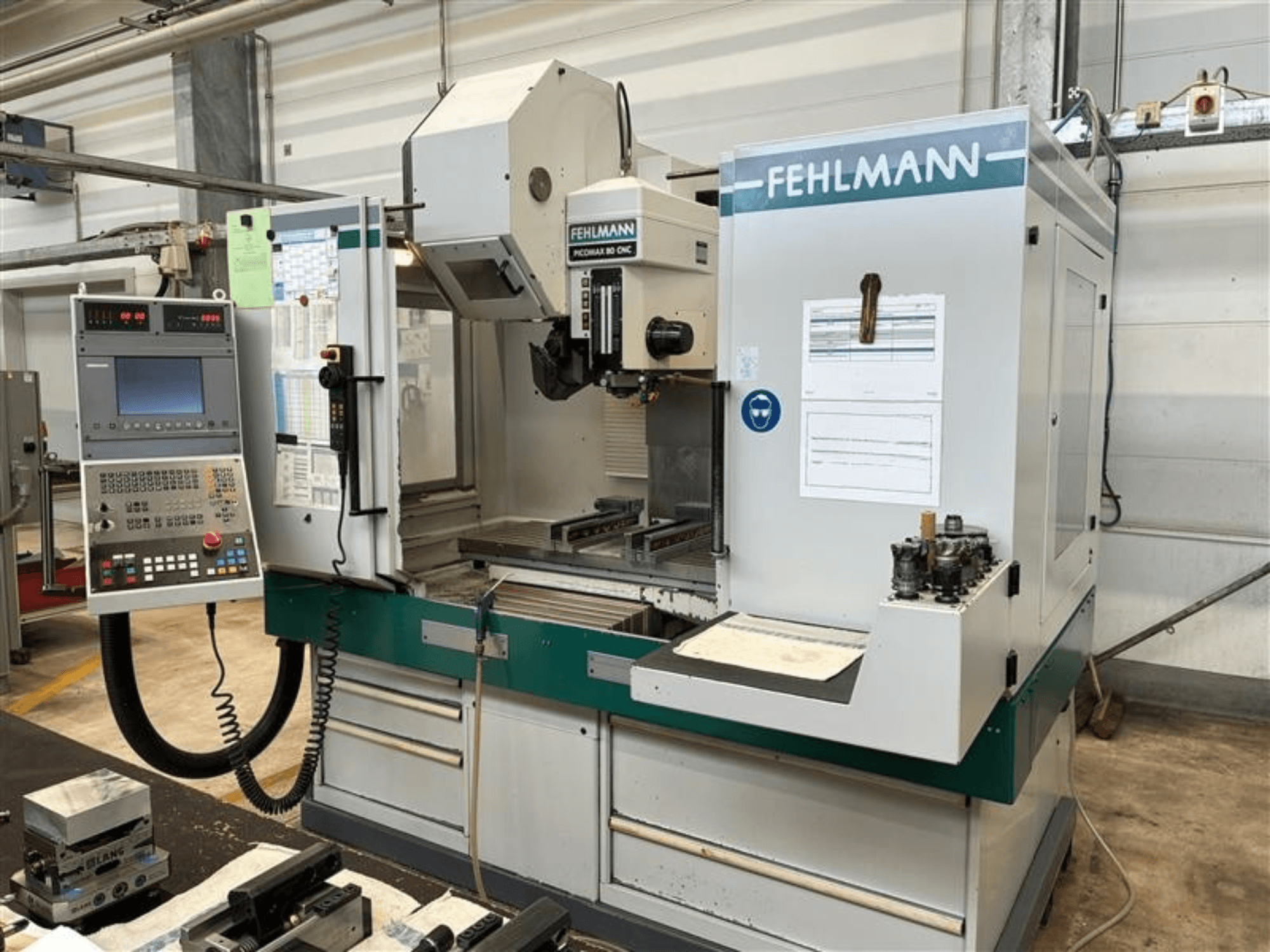 Vertikalusis apdirbimo centras „FEHLMANN PICOMAX 80 CNC-W 2/3“, vaizduojamas iš priekio, su valdymo pultu ir apdirbimo darbo zona.