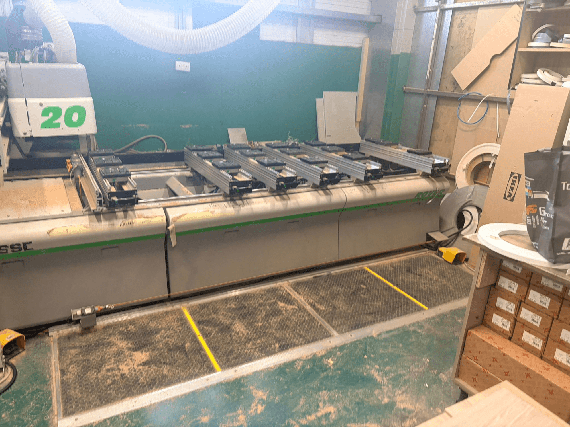 CNC medienos apdirbimo centras BIESSE ROVER 20, vaizdas iš priekio, su bėgių sistema, valdikliais ir ant paviršiaus matomomis pjuvenomis.
