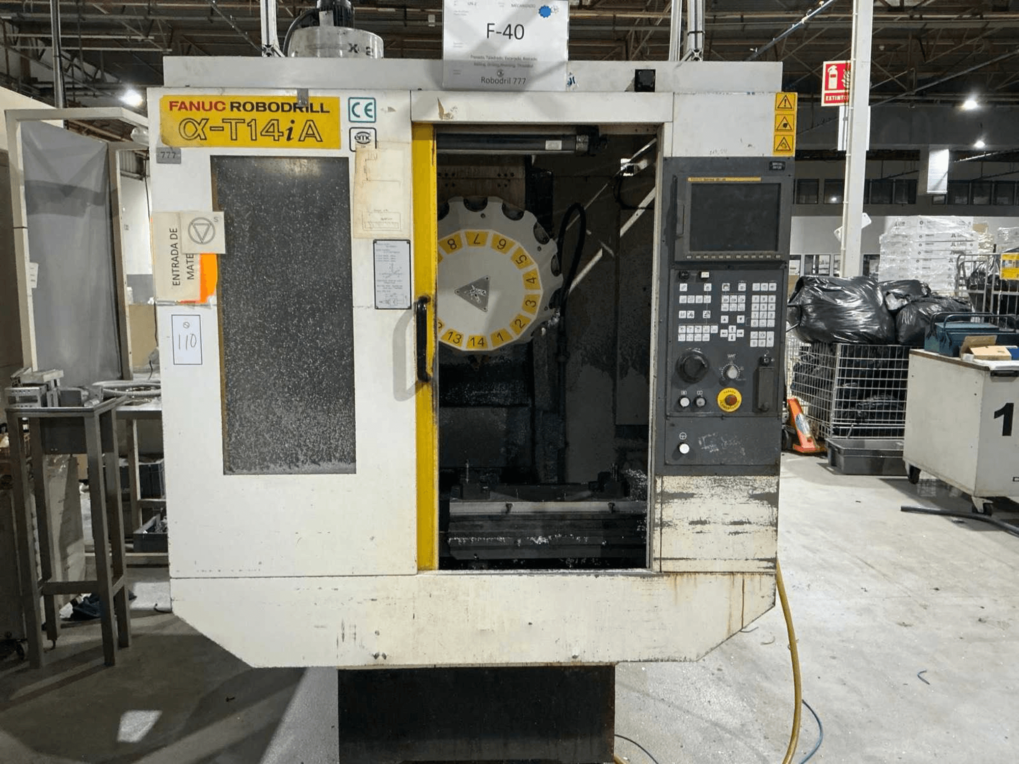 FANUC ROBODRILL α-T14iB vertikalusis apdirbimo centras, priekinis vaizdas, kuriame matomas valdymo skydelis ir įrankių karuselė.