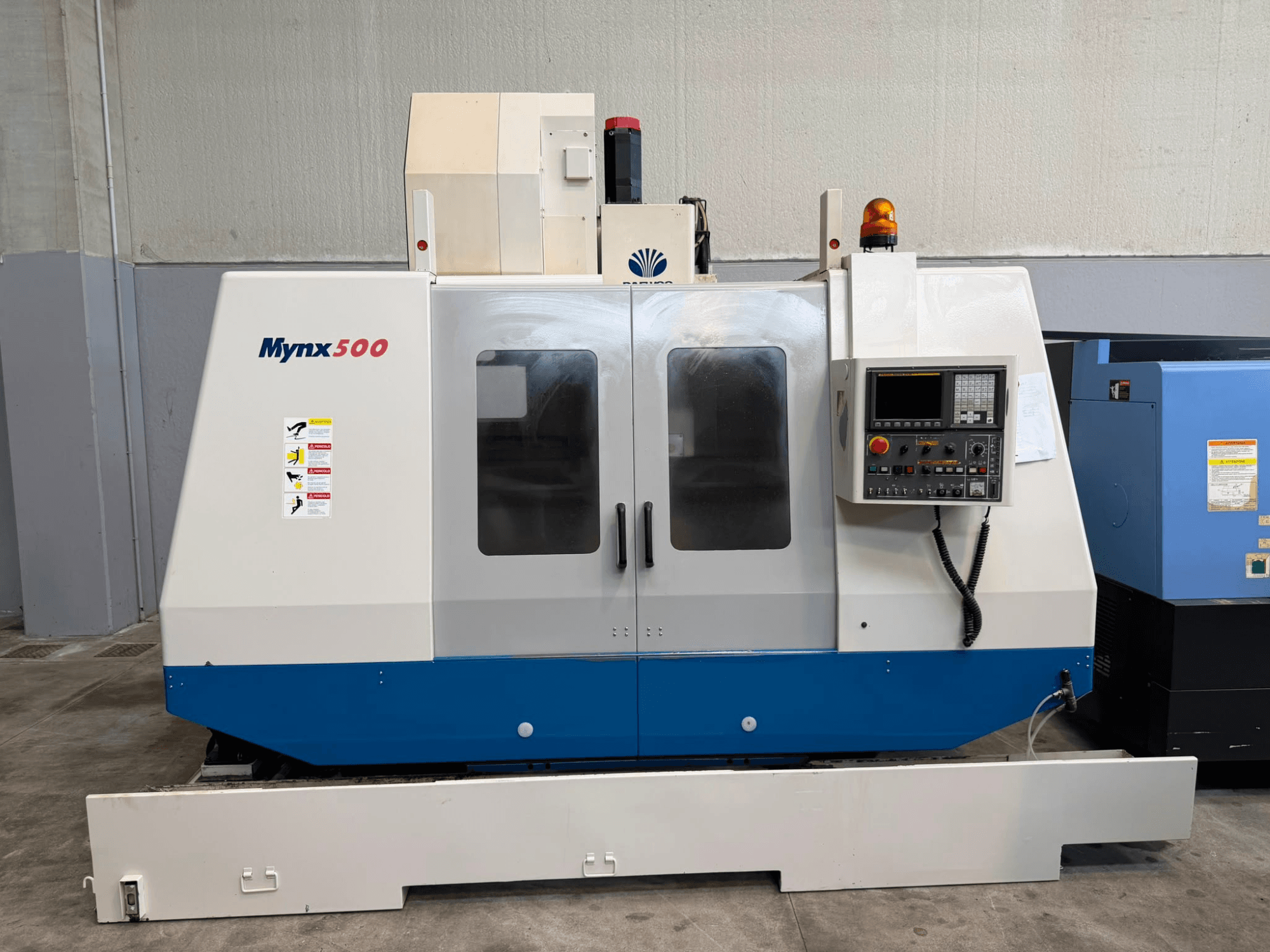 „DAEWOO MYNX 500“ vertikalusis apdirbimo centras, vaizdas iš priekio: matomas valdymo pultas, saugos lemputės ir lengvai atidaromos durys.