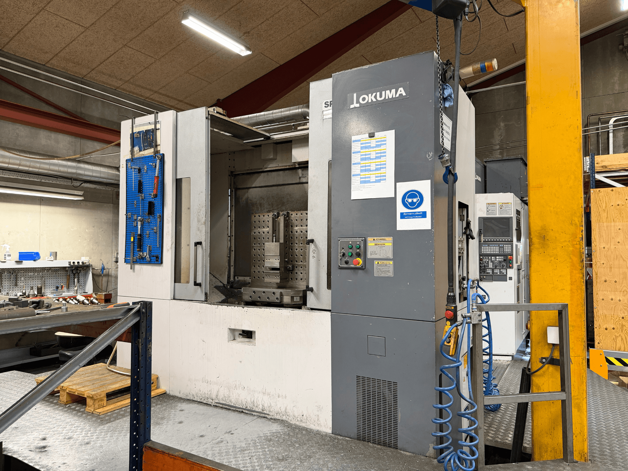 „Okuma MA-600HB“ horizontalus apdirbimo centras dirbtuvėse, vaizdas iš priekio, kuriame matomas valdymo skydas ir darbo zona.