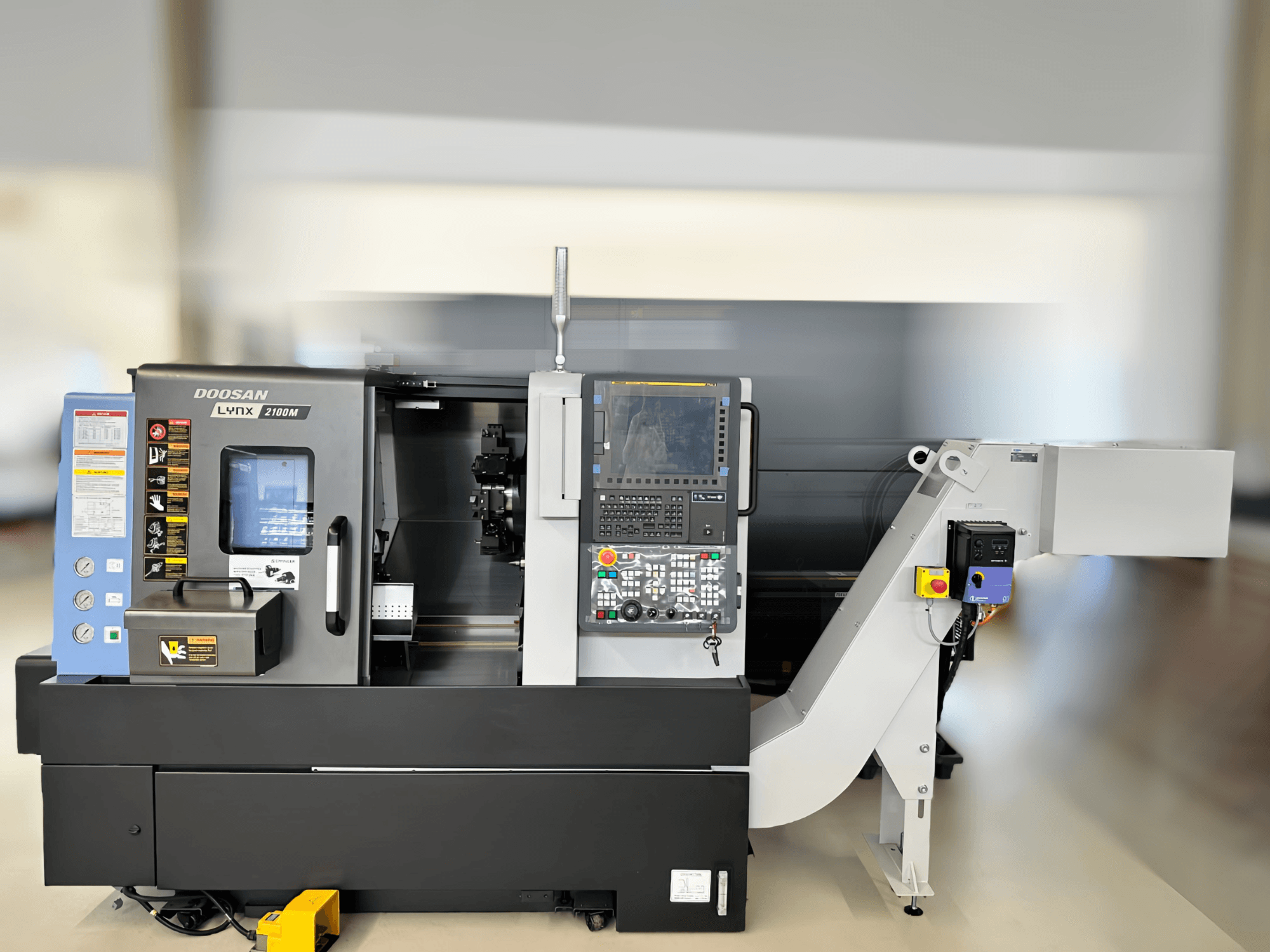 DN SOLUTIONS LYNX 2100MB horizontaliųjų tekinimo staklių priekinis vaizdas, kuriame matyti valdymo skydelis ir darbo zonos detalės.
