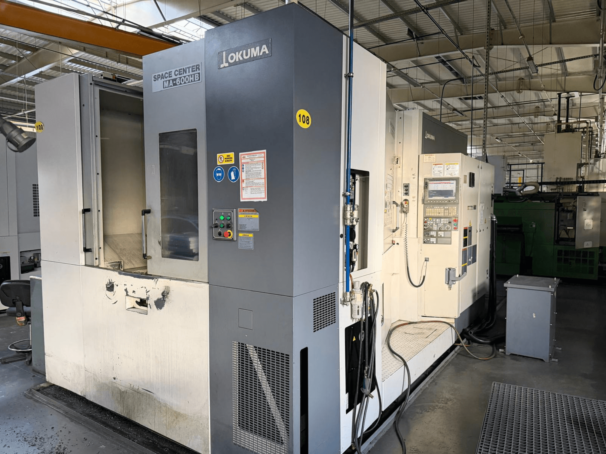 Okuma MA-600 HB horizontalusis apdirbimo centras, priekinis vaizdas, matomas valdymo skydelis ir pjovimo zona su matomomis nusidėvėjimo žymėmis.