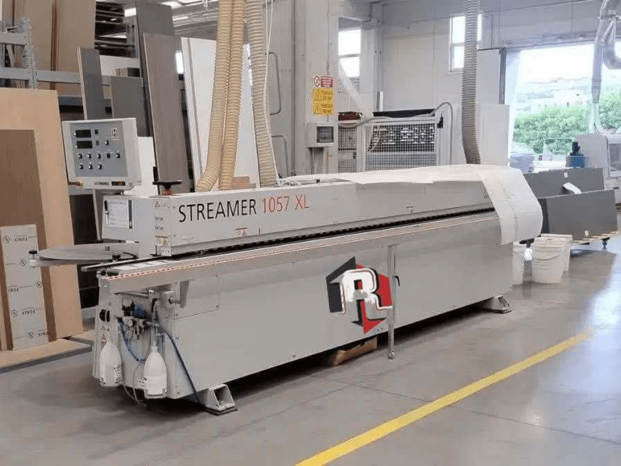 „HOLZHER STREAMER 1057 XL“ kraštų apdirbimo staklės dirbtuvėse, vaizdas iš šono, kuriame matomas valdymo skydelis ir oro žarnos.