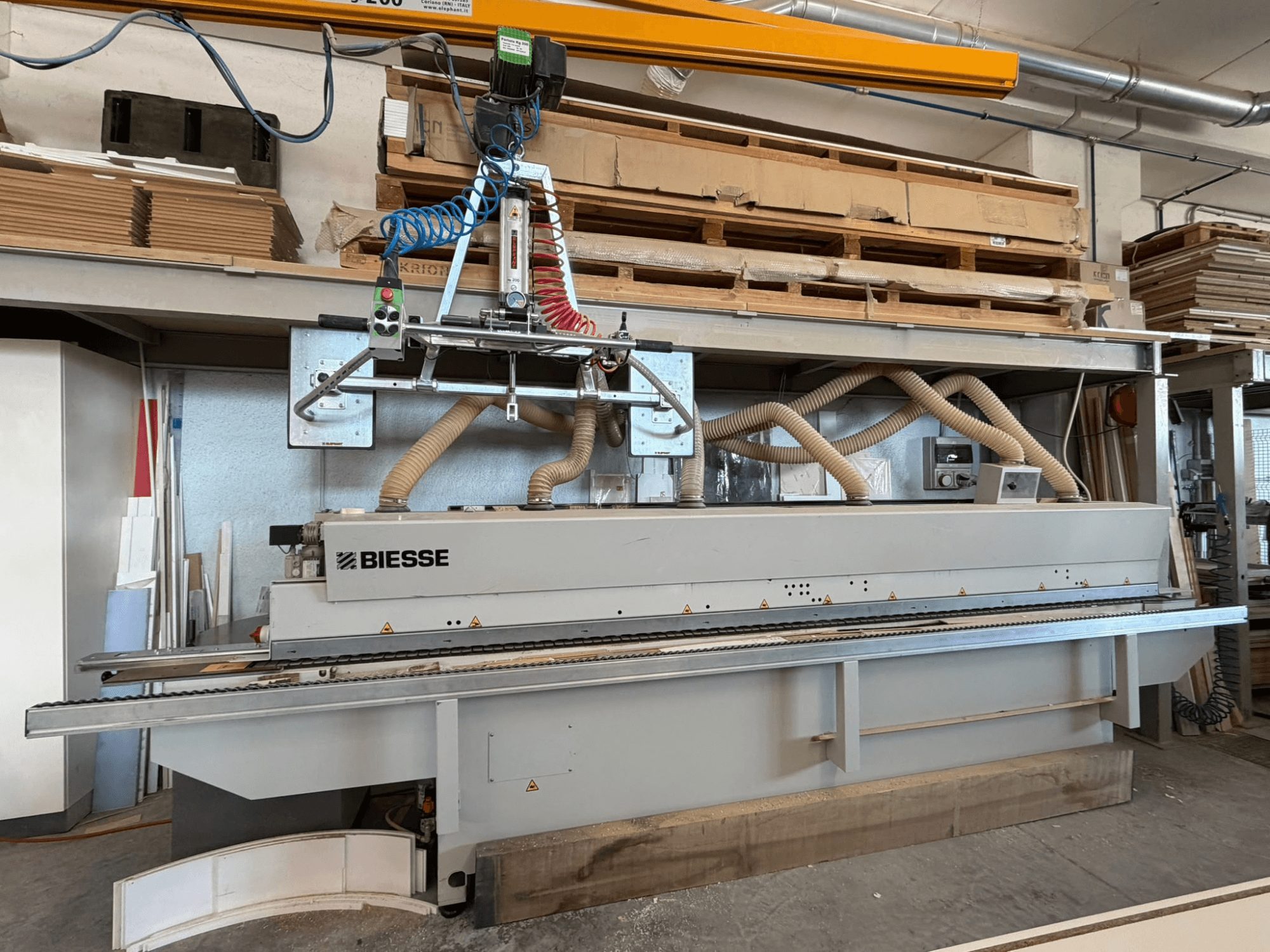„BIESSE AKRON 1330“ kraštų apdirbimo staklės dirbtuvėse: vaizdas iš priekio su valdymo pultu ir dulkių surinkimo sistema.