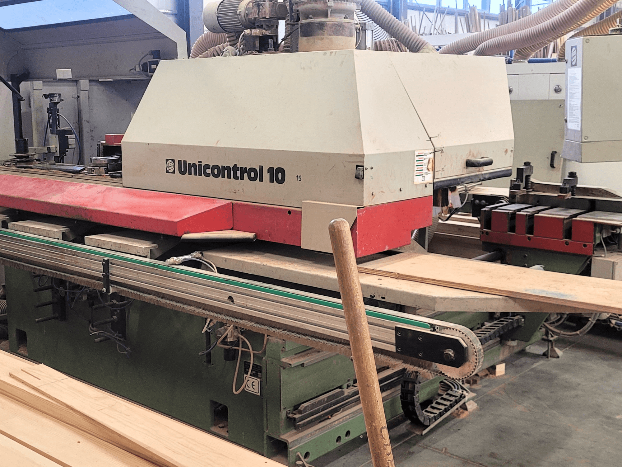 WEINIG/DIMTER CNC apdirbimo centras "Unicontrol 10", vaizdas iš priekio su medinėmis lentomis ir įranga dirbtuvėse.