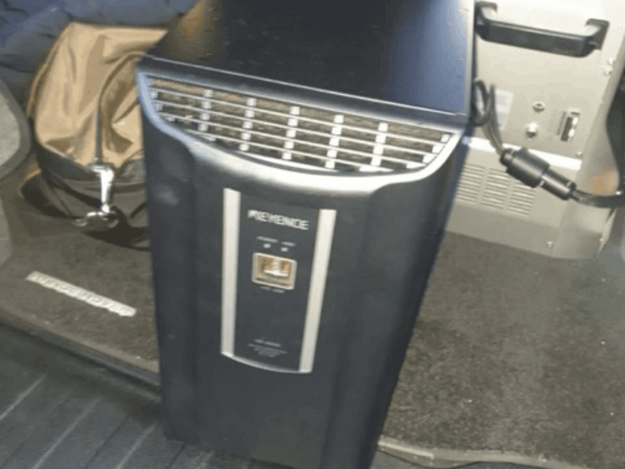 Automatikos sistemos KEYENCE IM-8030 priekinis vaizdas, kuriame matyti valdymo skydelis ir ventiliacijos angos automobilio salono fone.