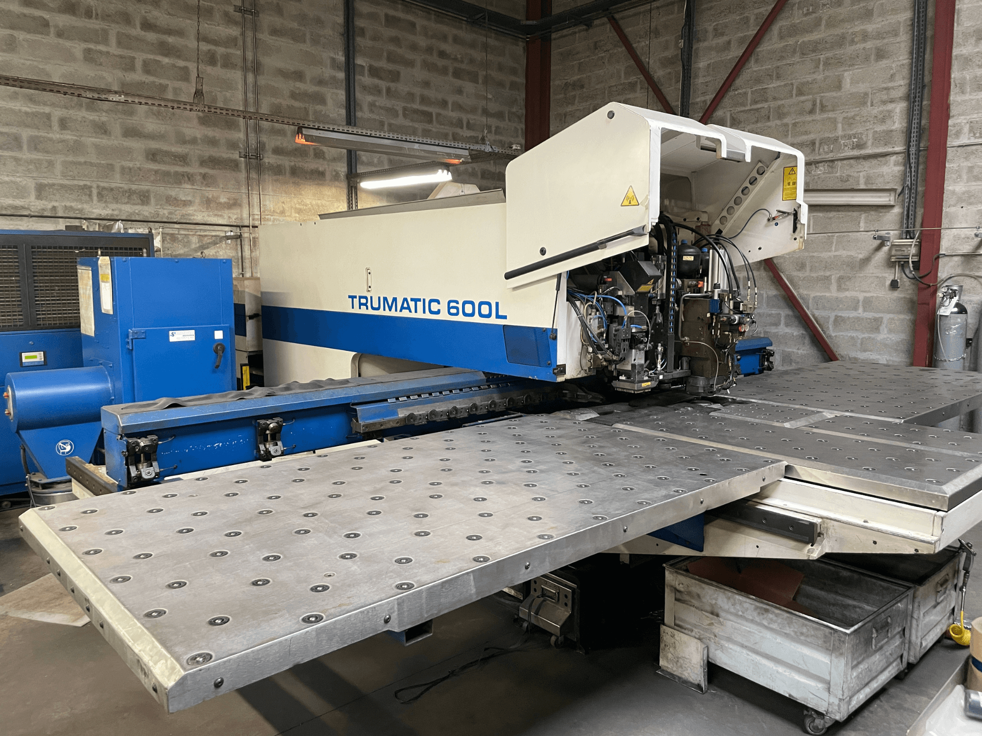 CO2 lazerinio pjaustymo staklės TRUMPF TRUMATIC TC 600L, vaizdas iš priekio, matomas metalo pjaustymo stalas ir valdymo skydelis.