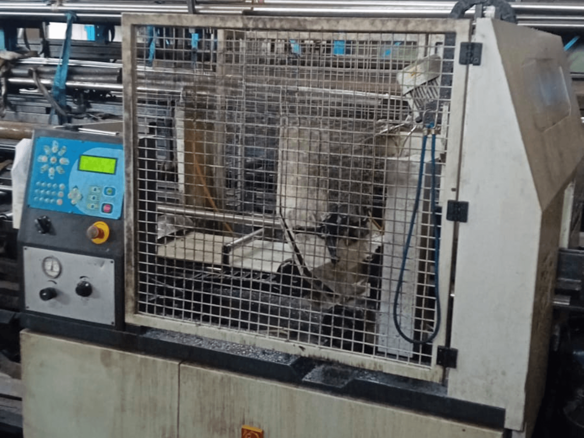 Metalo juostinis pjūklas Macc 381 AV, priekinis vaizdas, kuriame matyti valdymo skydelis, apsauginis narvelis ir metalo dirbinių nuolaužos ant pagrindo.