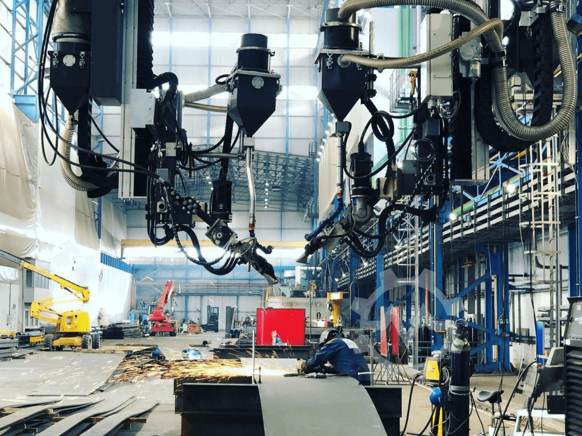 Robotizuota pjovimo mašina pramoninėje aplinkoje, iš šono žiūrint į kibirkštis; turi daugybę priedų ir žarnų.