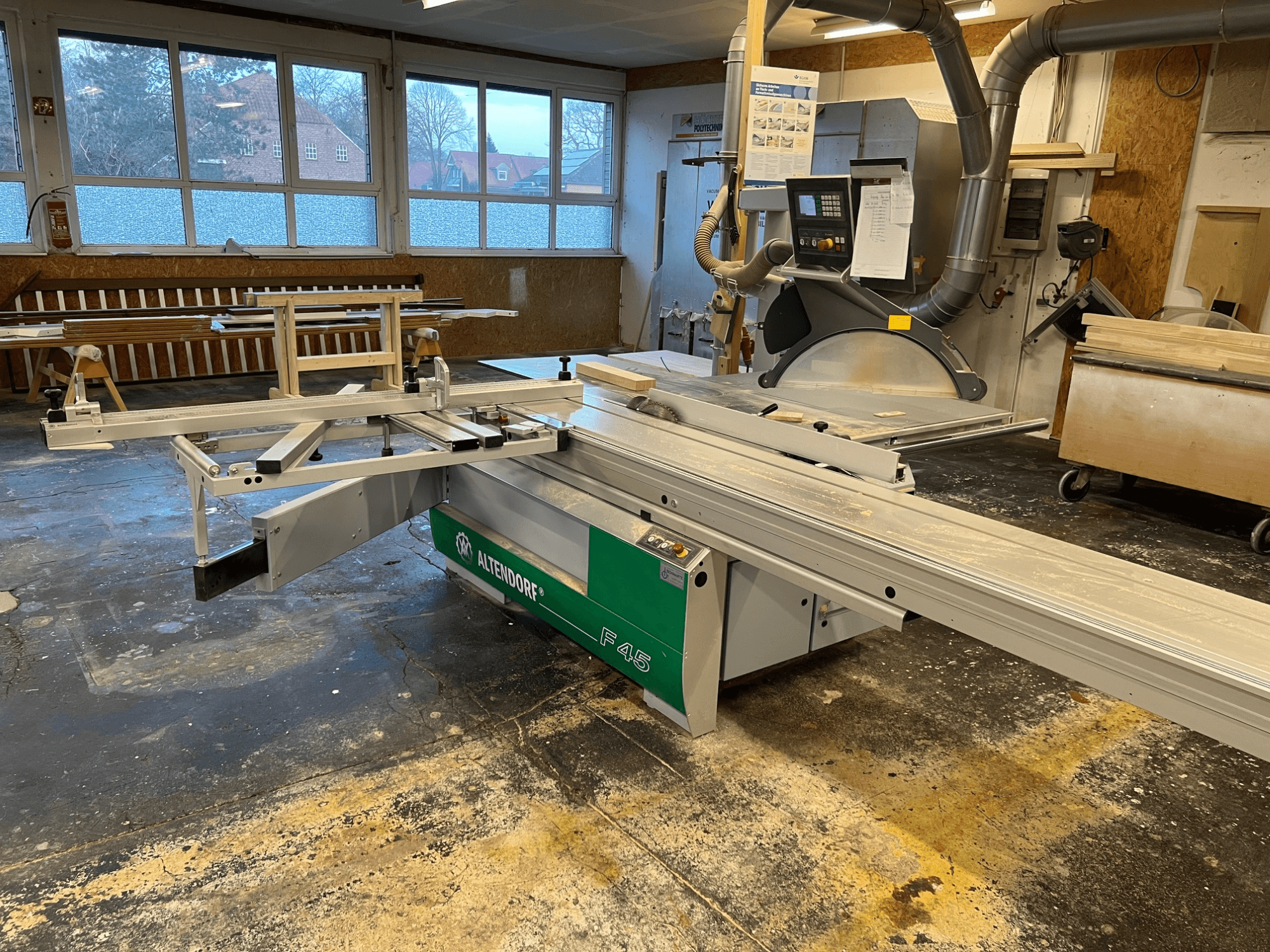 Stalo pjūklas "Altendorf F45" dirbtuvėse, iš priekio matoma reguliuojama svirtis ir valdymo skydelis, idealiai tinka tikslioms pjovimo užduotims atlikti.