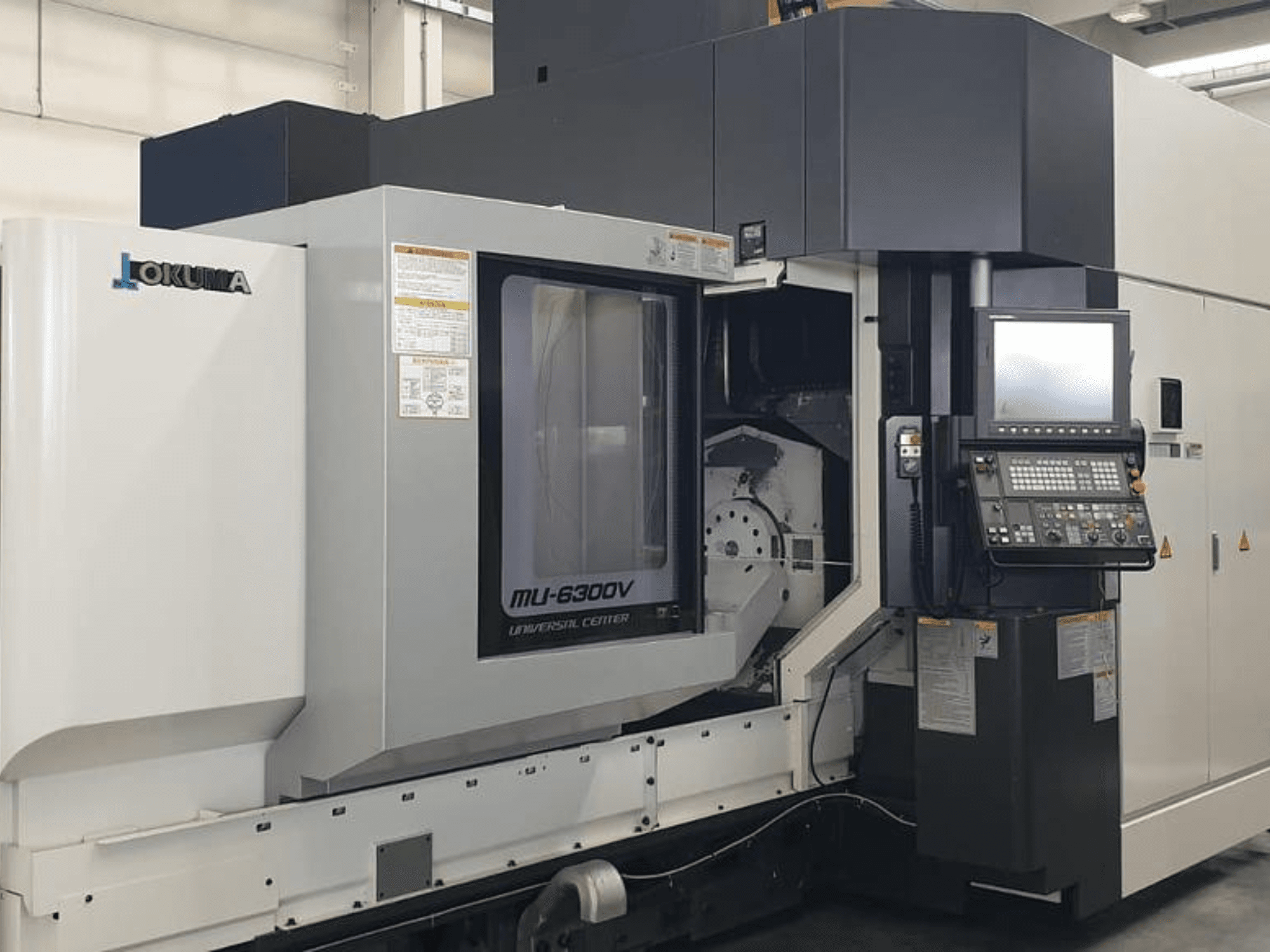 "Okuma MU 6300 V" vertikalaus apdirbimo centras, priekinis vaizdas, kuriame matomas valdymo skydelis ir apdirbimo zonos detalės.