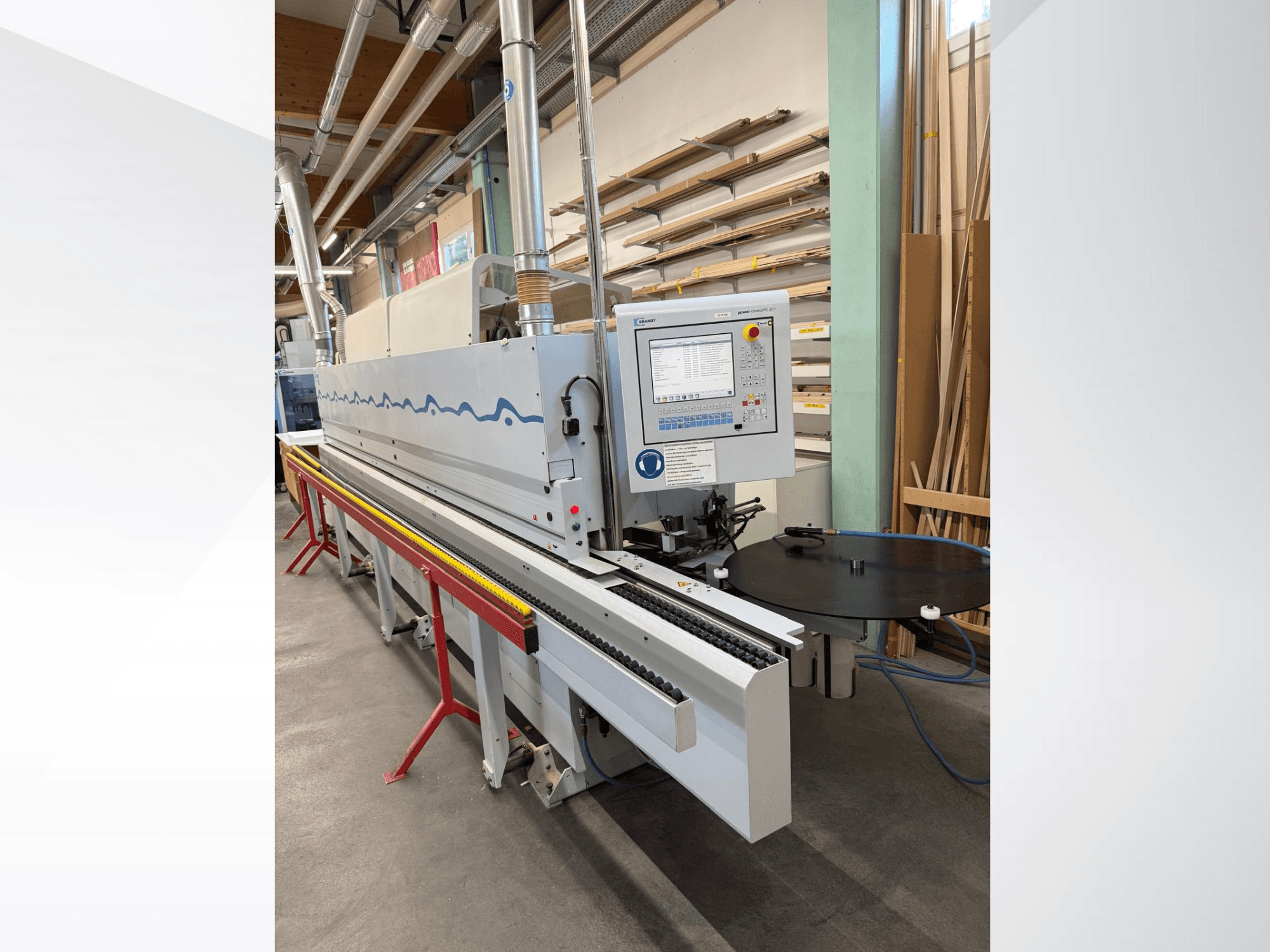 "HolzHer" automatinės kraštų apklijavimo mašinos su valdymo skydeliu, transportavimo sistema ir apvaliu atraminiu stalu vaizdas iš priekio.