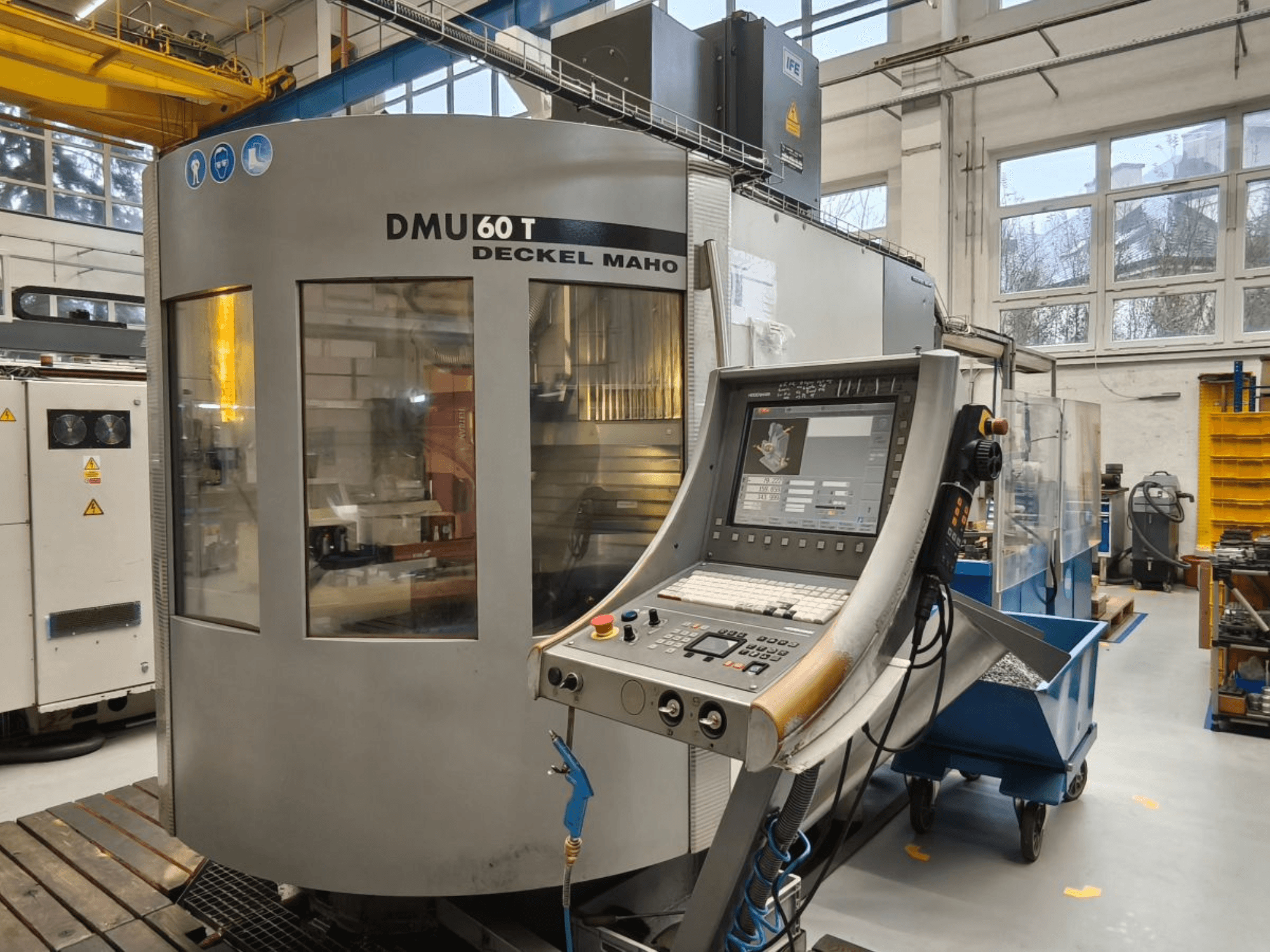 Vertikalus DECKEL MAHO DMU 60T mechaninio apdirbimo centro su valdymo pultu, kuriame rodomi tikslūs įrankiai, vaizdas dirbtuvėse.
