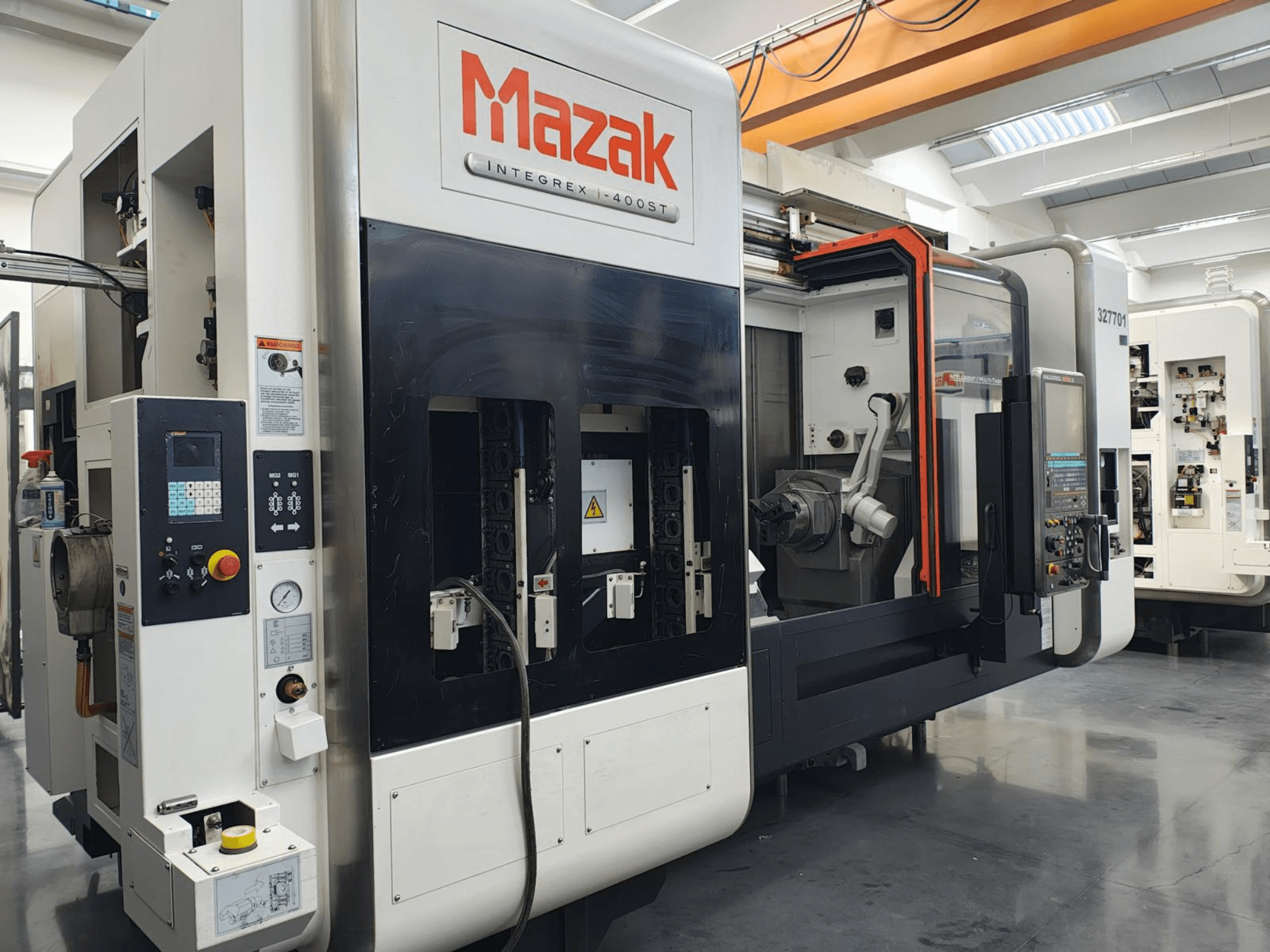 Mazak Integrex 400ST, vaizdas iš priekio; CNC staklės su valdymo skydeliu, verpstėmis ir roboto ranka, matomos dirbtuvėse.